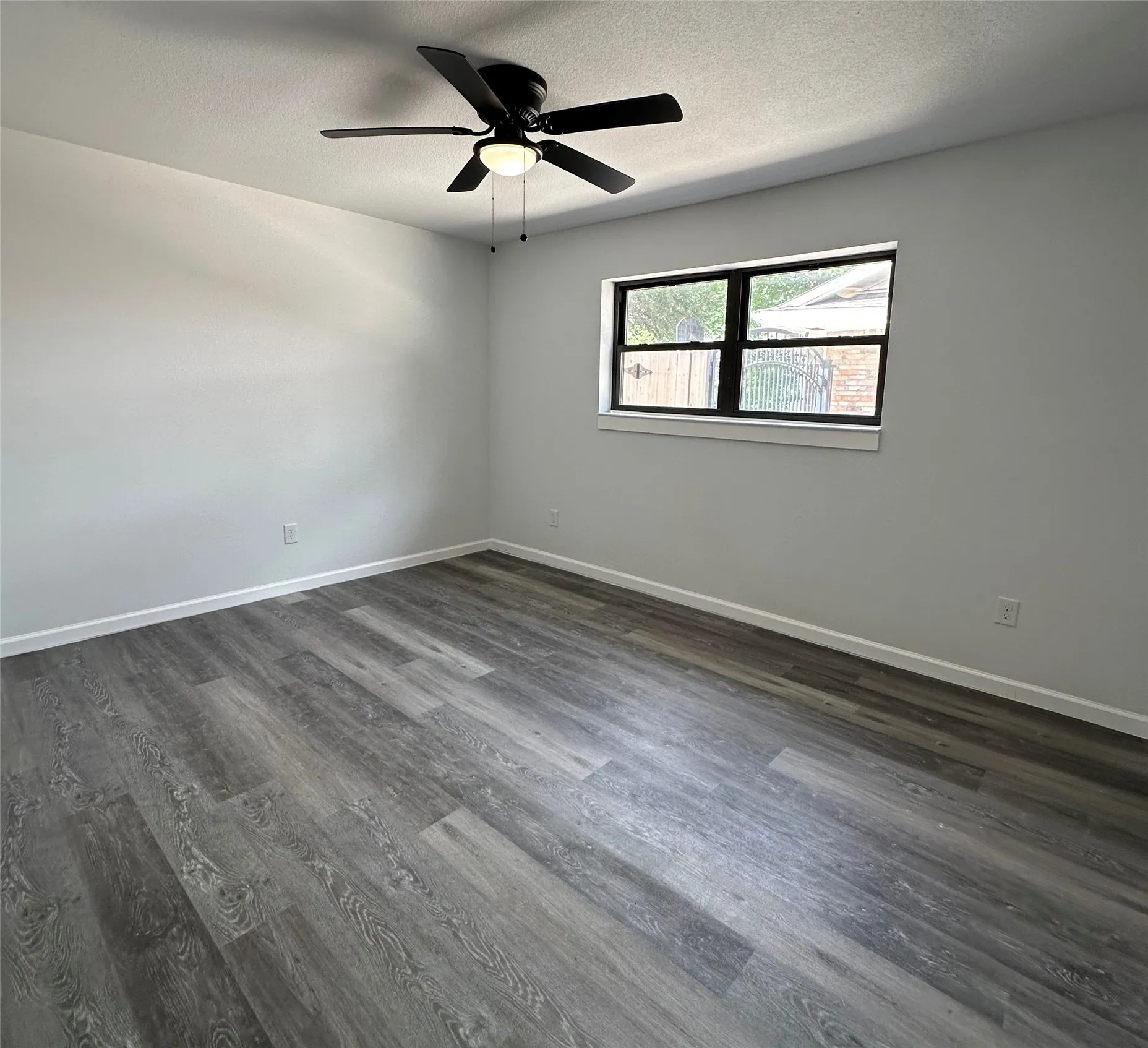 Wood-finish flooring with a neutral paint palette and a ceiling fan with integrated lighting
