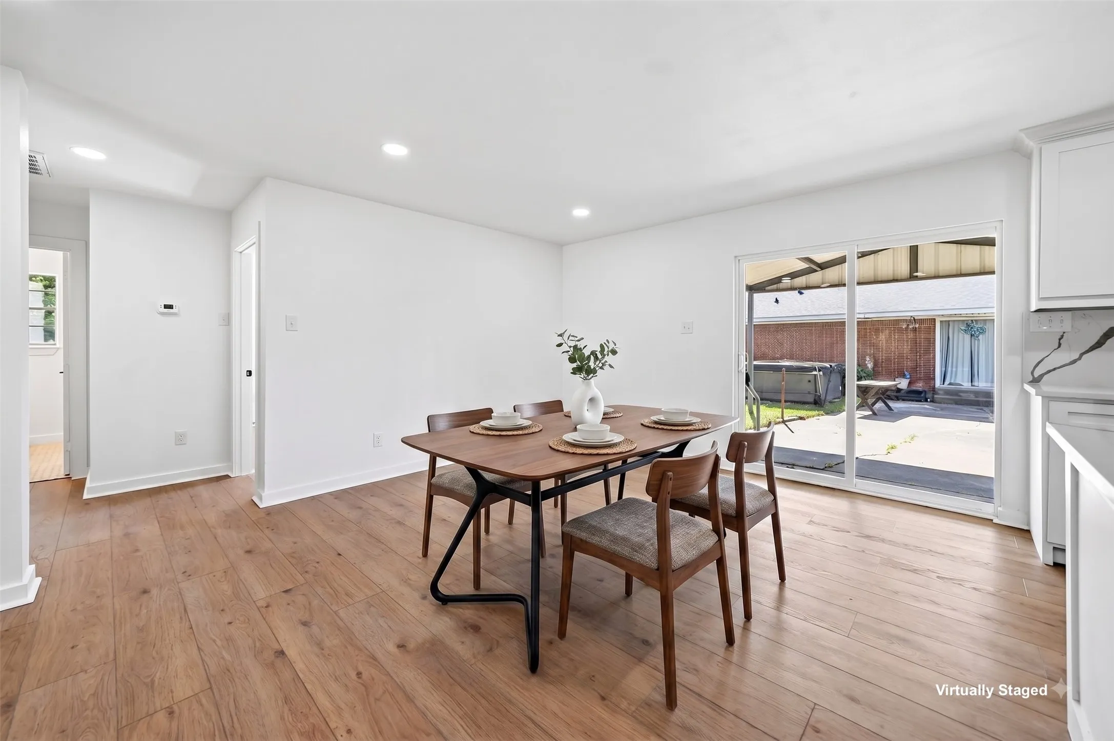 Recessed lighting, wood-finish flooring, white walls, white cabinetry, and sliding glass doors