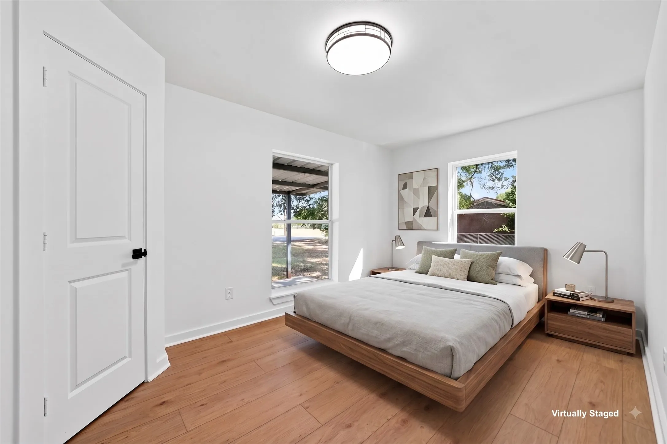 Hardwood-style flooring, bright white walls, modern flush mount ceiling light fixture, and two windows