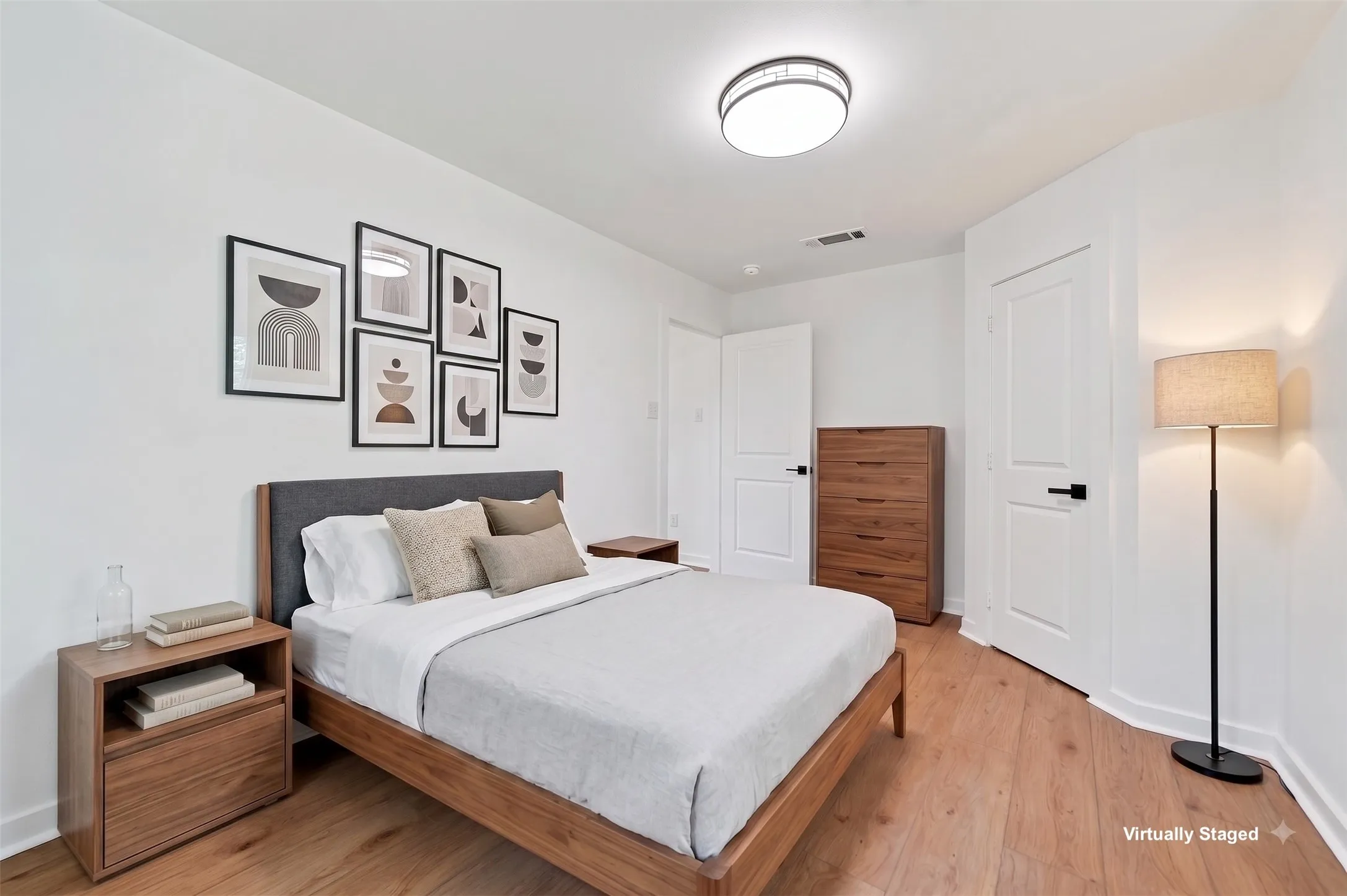 Wood-finish flooring, white walls, two white panel doors, and a flush-mount ceiling light fixture