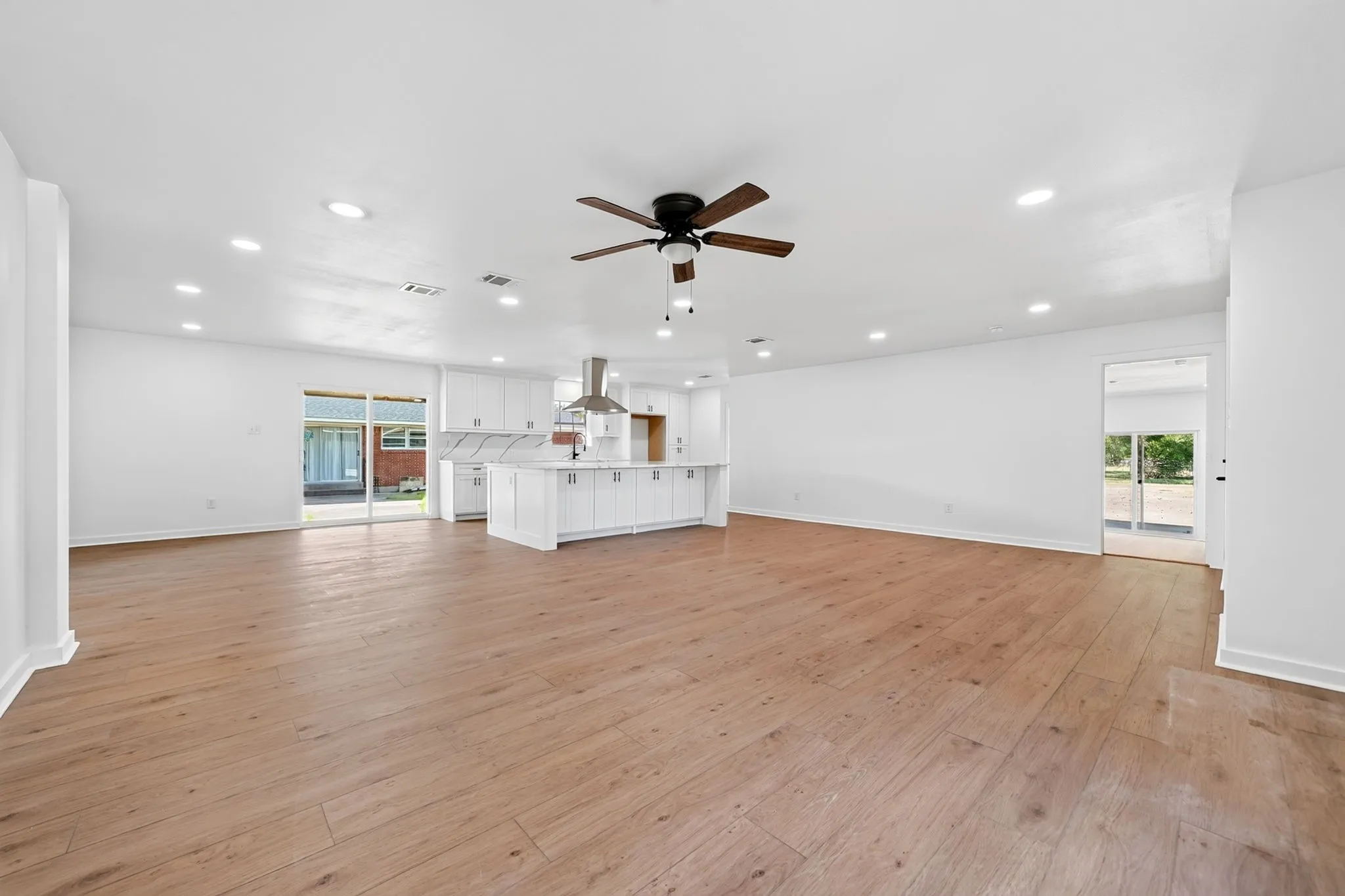 Expansive open-concept living area featuring wood-finish flooring, recessed lighting, and a ceiling fan