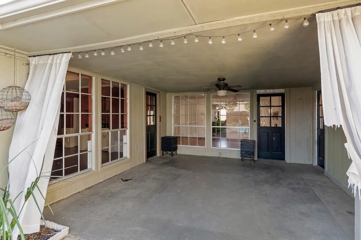 Covered patio featuring a ceiling fan, multiple large windows, and a glass-paneled door