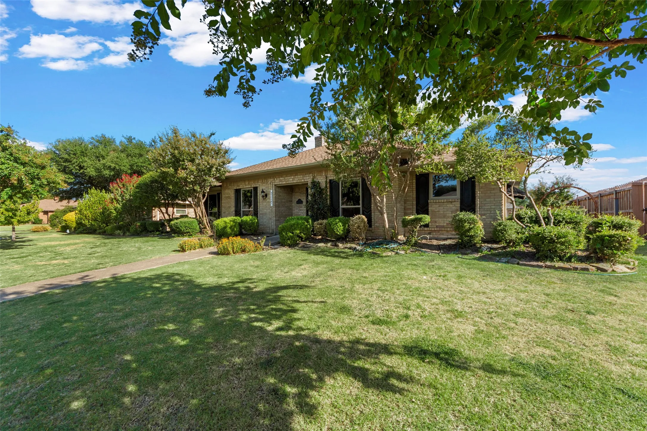 Brick exterior, manicured lawn, established landscaping, walkway, mature trees