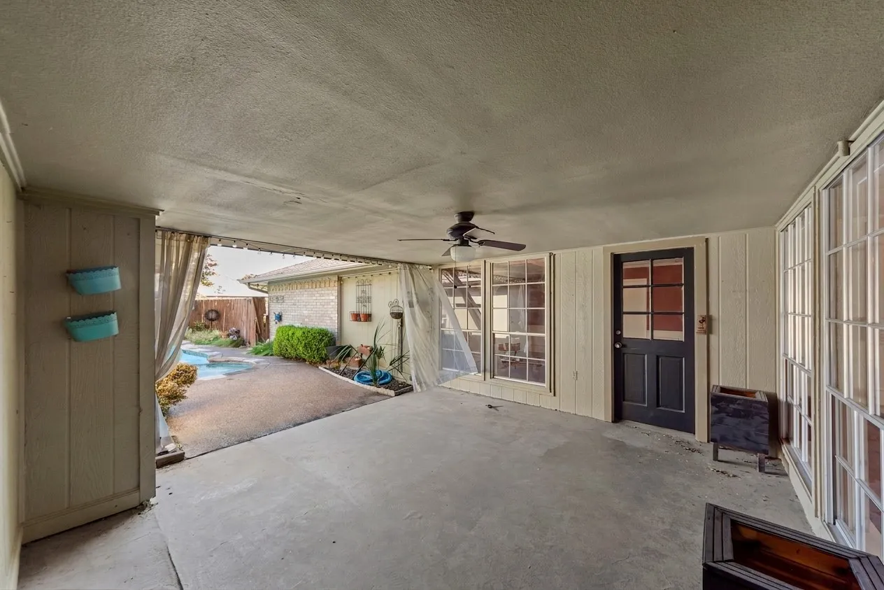Covered patio featuring a concrete slab, ceiling fan, and multiple window panels