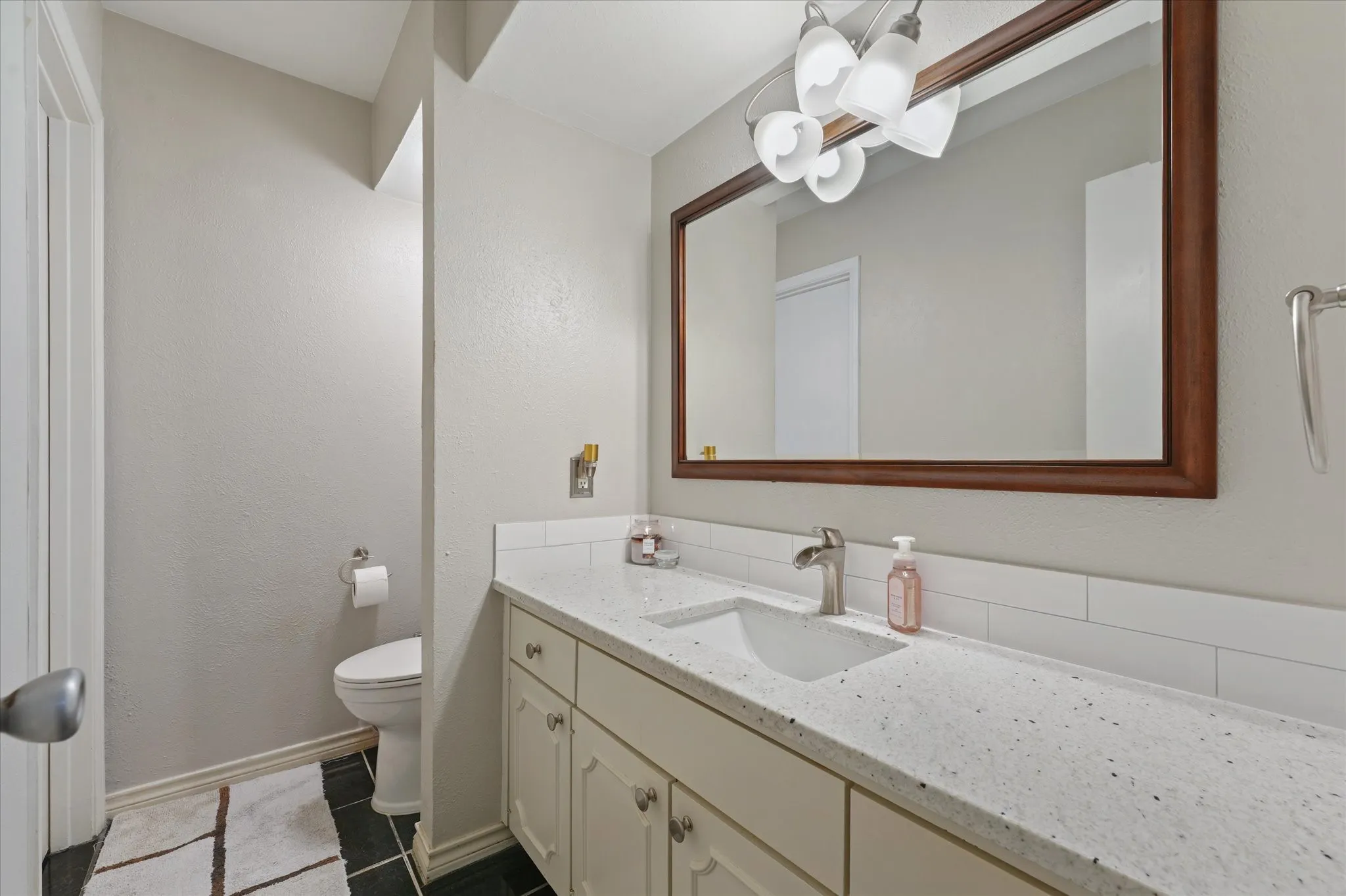 Vanity with a speckled countertop, undermount sink, and brushed nickel faucet