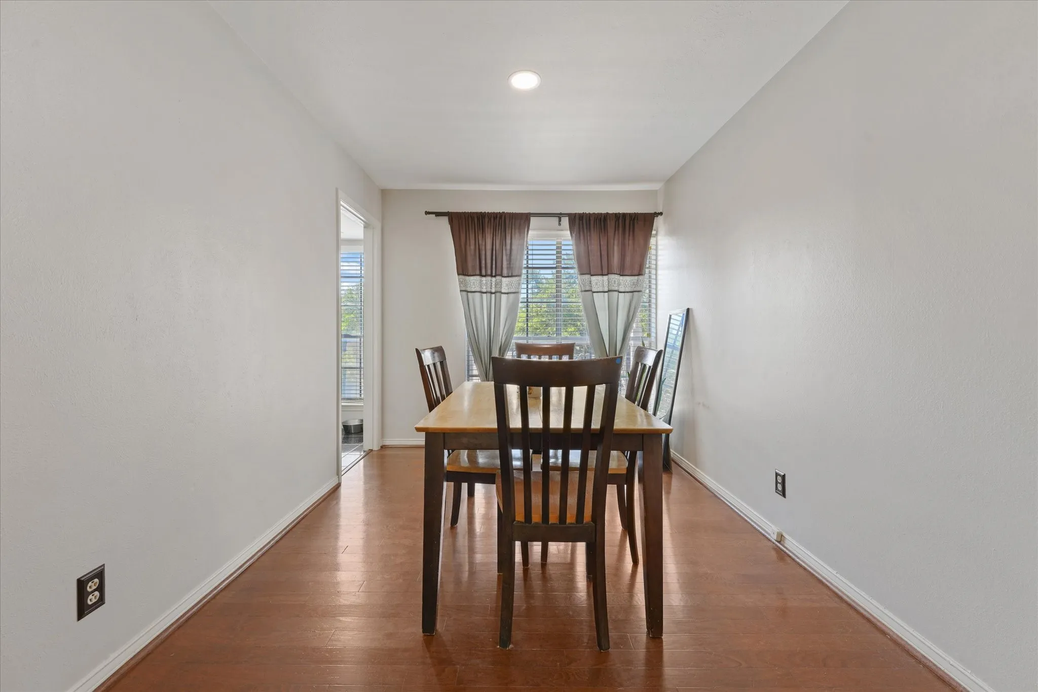 Wood-finish flooring with white walls and a recessed ceiling light