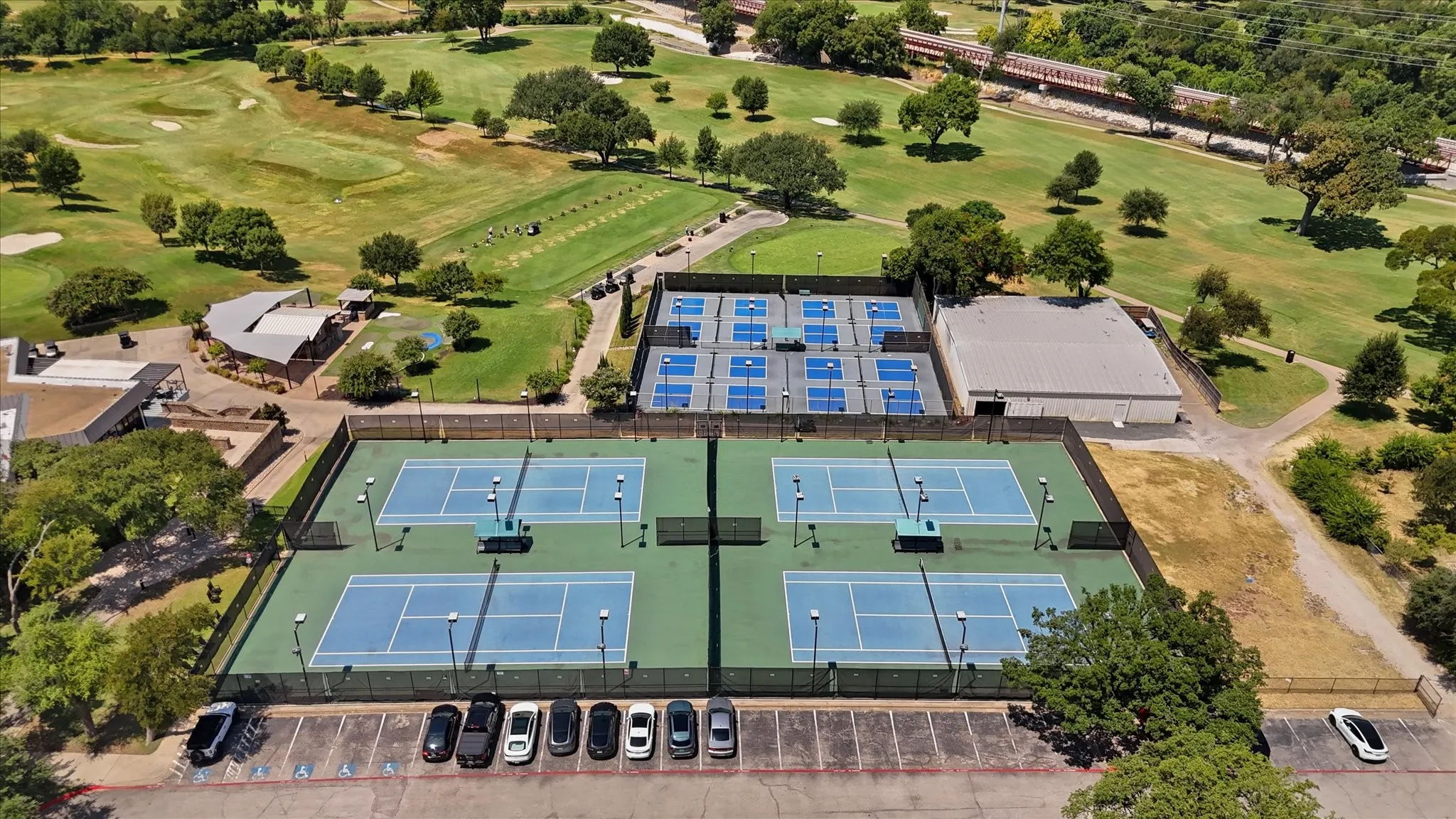 Four hard-surface tennis courts and multiple pickleball courts with perimeter fencing