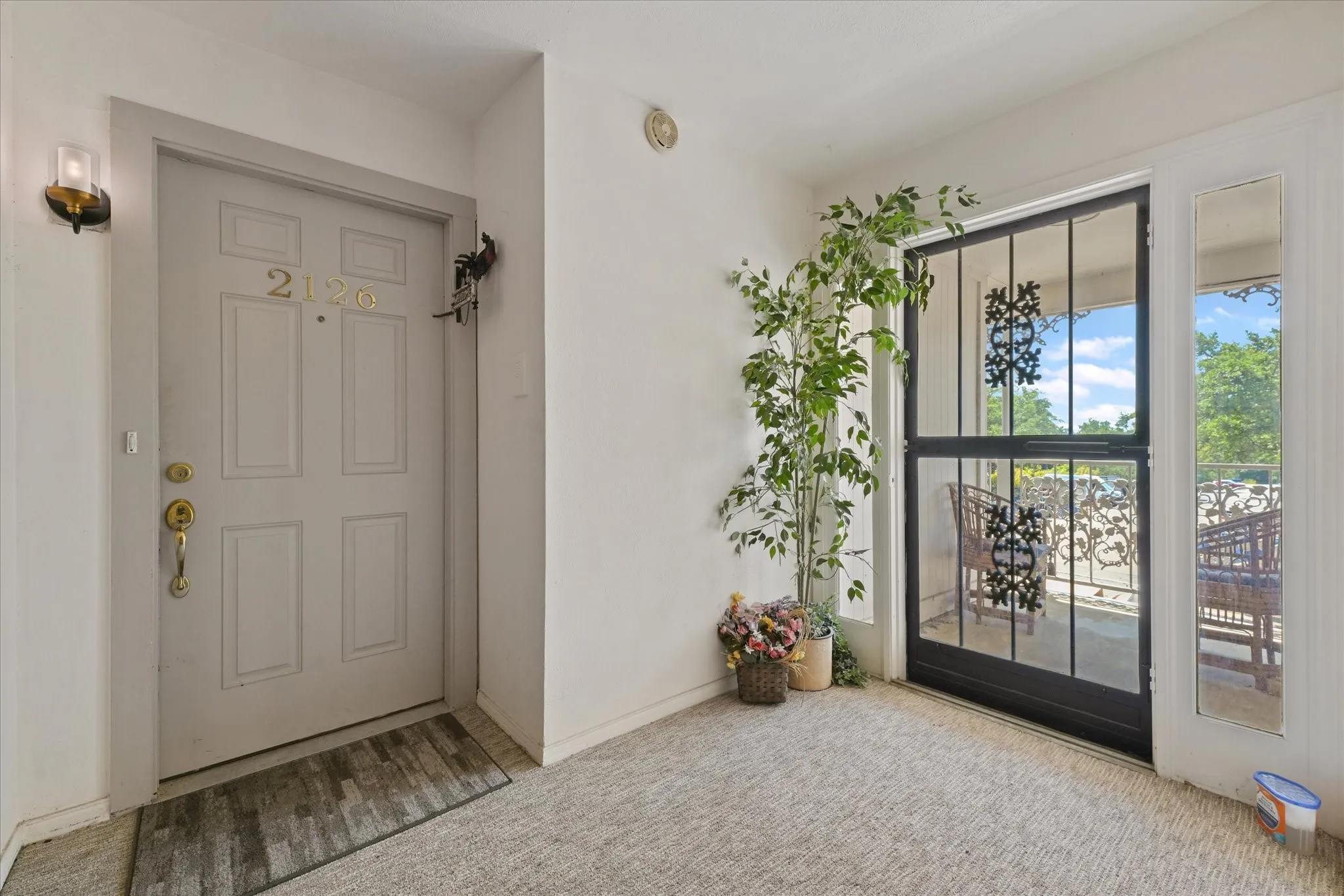 Entryway featuring a panel door with brass hardware, a wall-mounted sconce, and carpet flooring