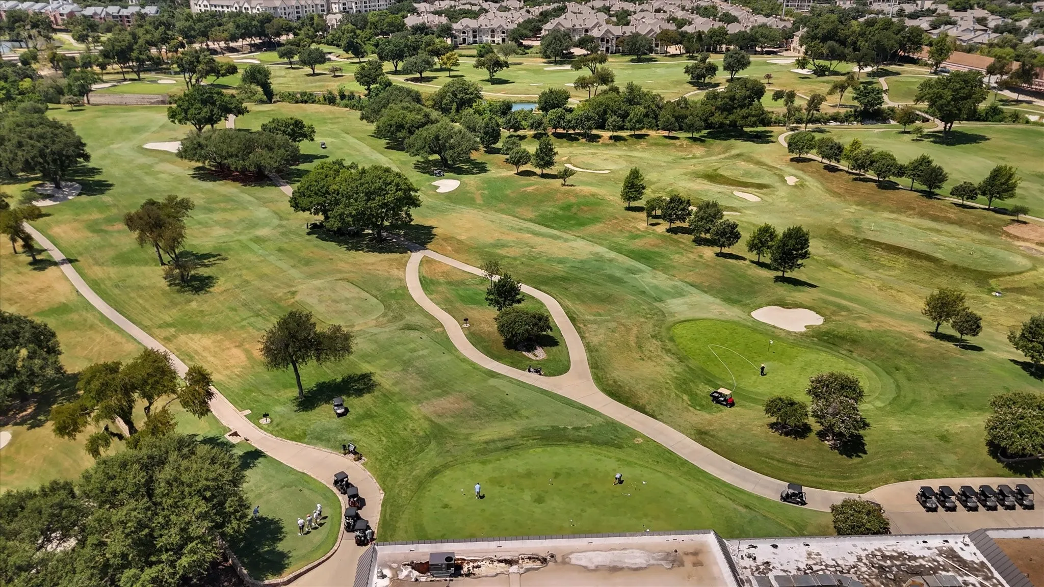 Expansive golf course featuring manicured greens, sand traps, paved cart paths, and mature trees