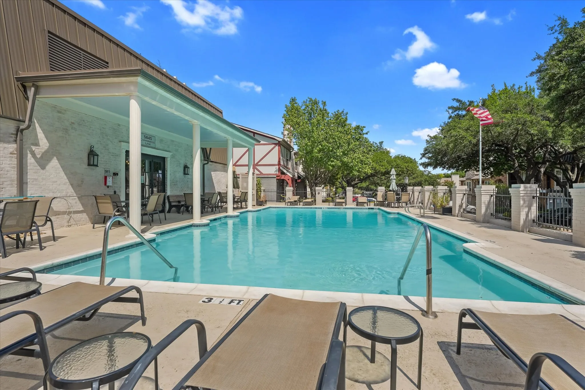 Swimming pool with a paved deck, an adjacent covered patio, and a privacy fence