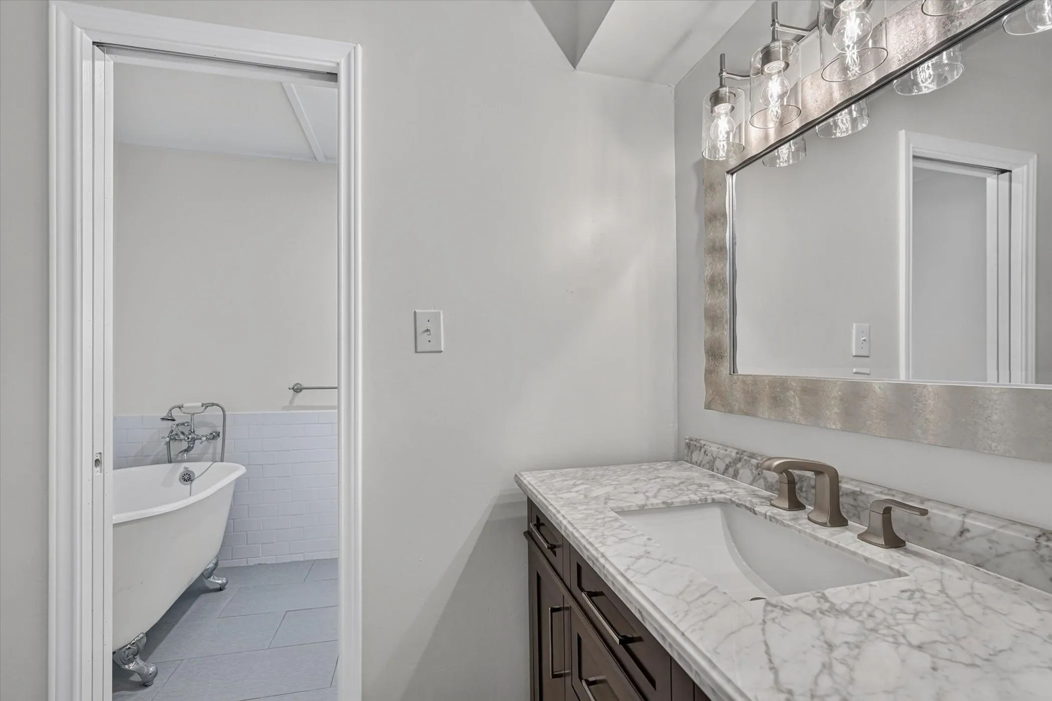 Vanity with a marble-patterned countertop, undermount sink, and brushed nickel faucet