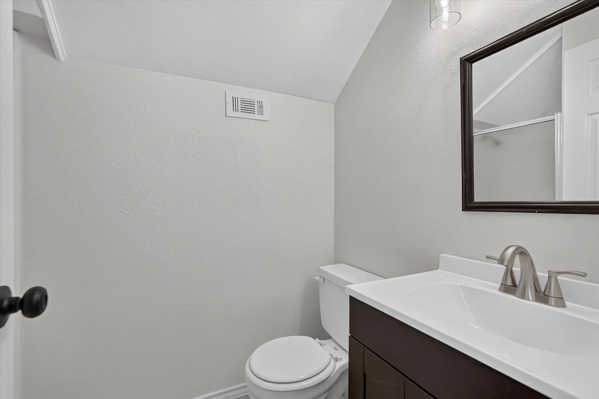 Dark wood-finish vanity with an integrated white sink and brushed nickel faucet