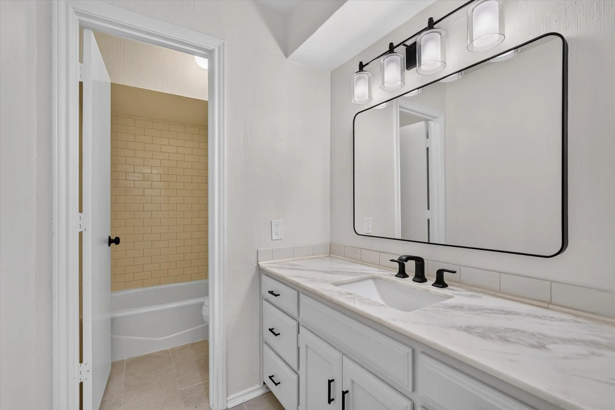 1st floor bathroom White vanity with panel-front cabinetry, a rectangular undermount sink, and a stone-finish countertop