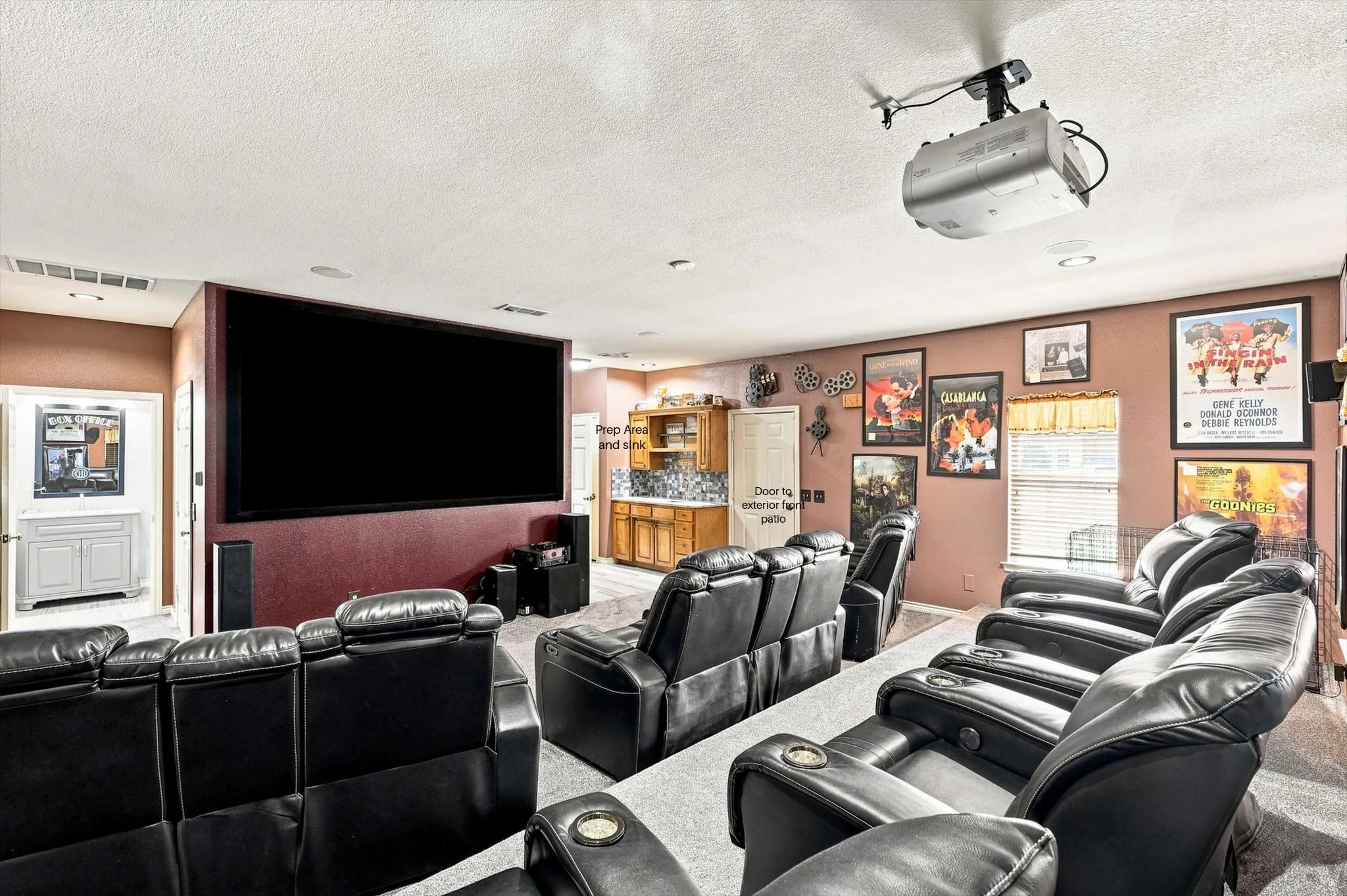 Full bath to upper left, media screen and equipment, and these comfy chairs stay with the home.  This can also be a parent suite as the door to upper right of photo opens to front porch and the added sink and prep area.