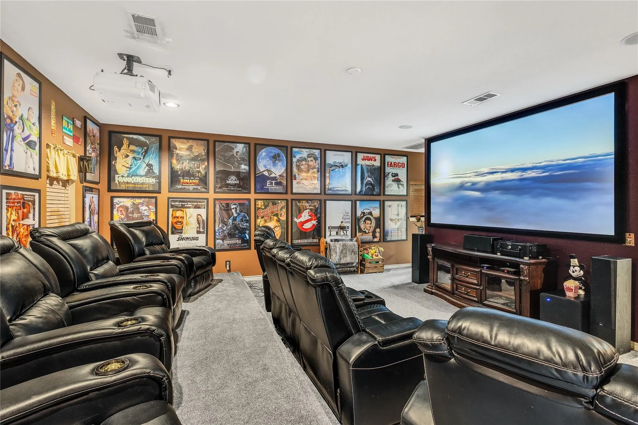 Dedicated media room with a large projection screen, mounted projector, and a built-in media console