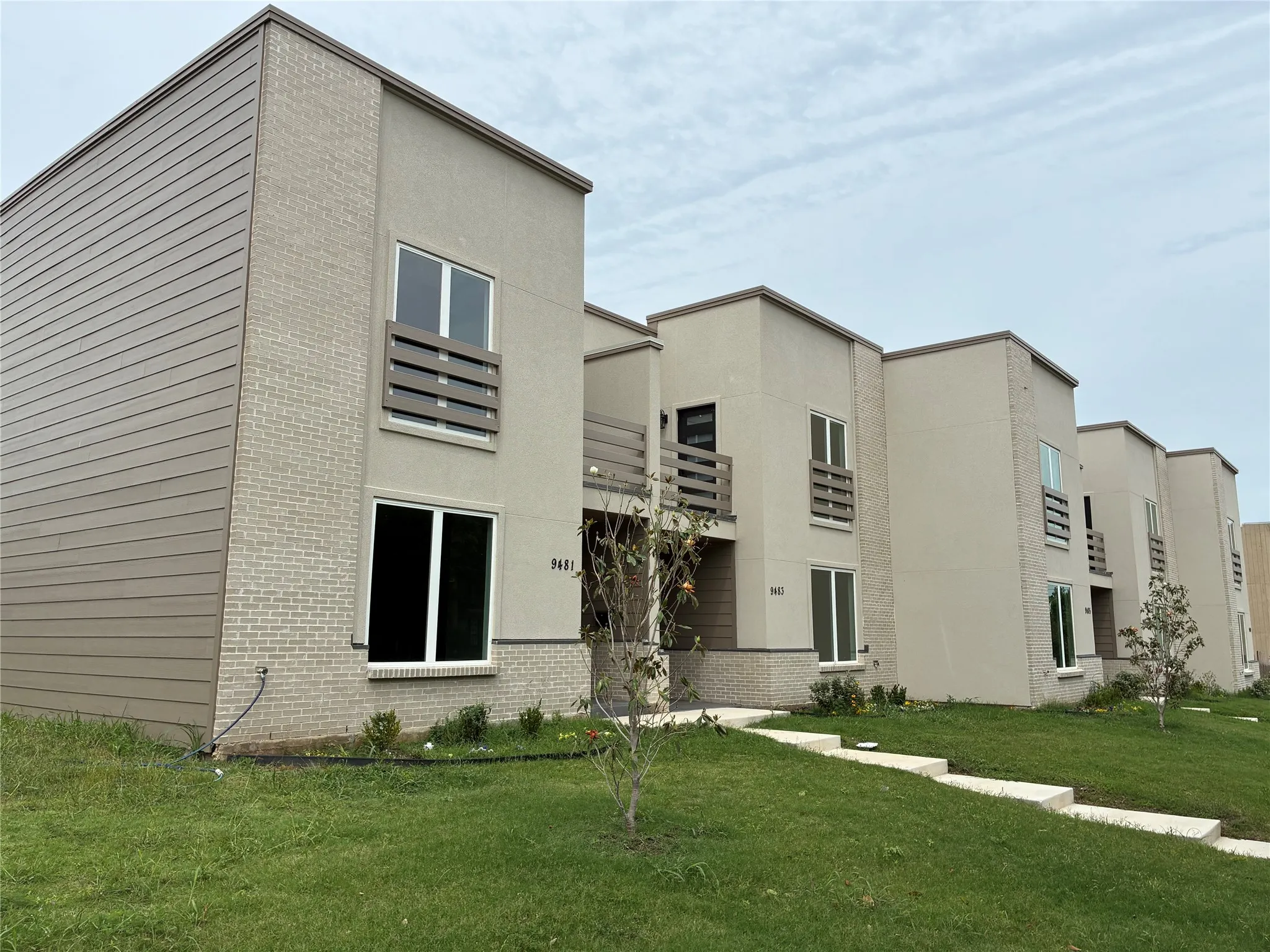 Multi-story residence featuring a combination of horizontal siding, light-colored brick, and stucco finishes