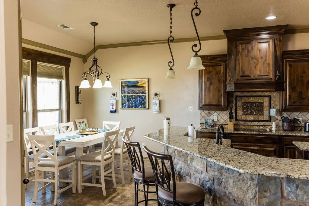 Stone-front breakfast bar with granite countertop, dark wood-finish cabinetry, tile backsplash with decorative inset, and recessed lighting