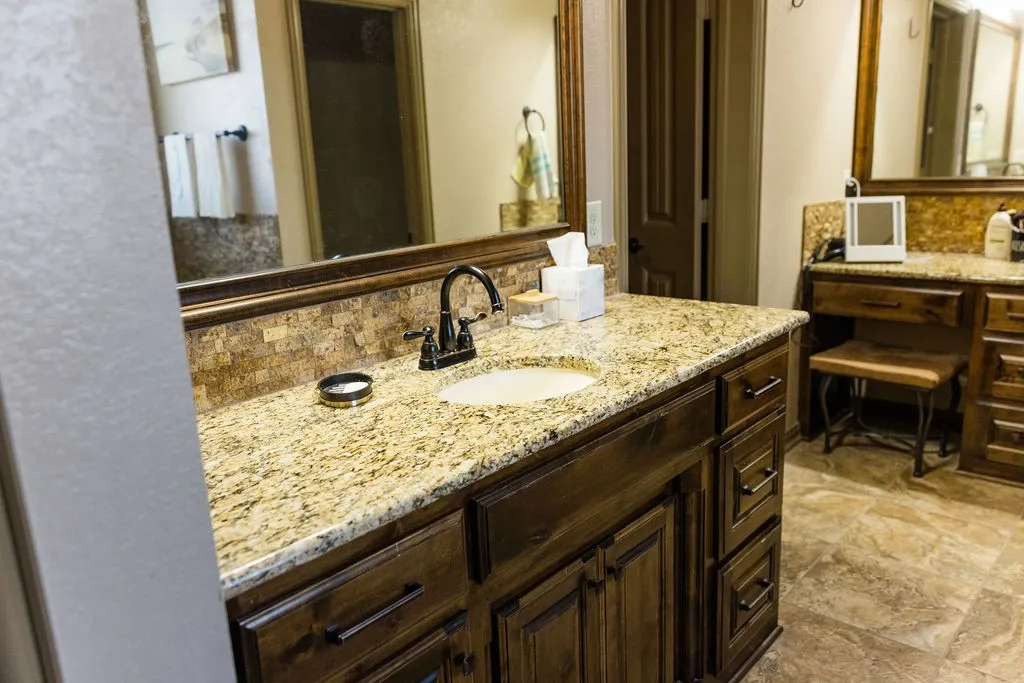 Dual vanity with granite countertops, wood cabinetry, and an integrated makeup vanity