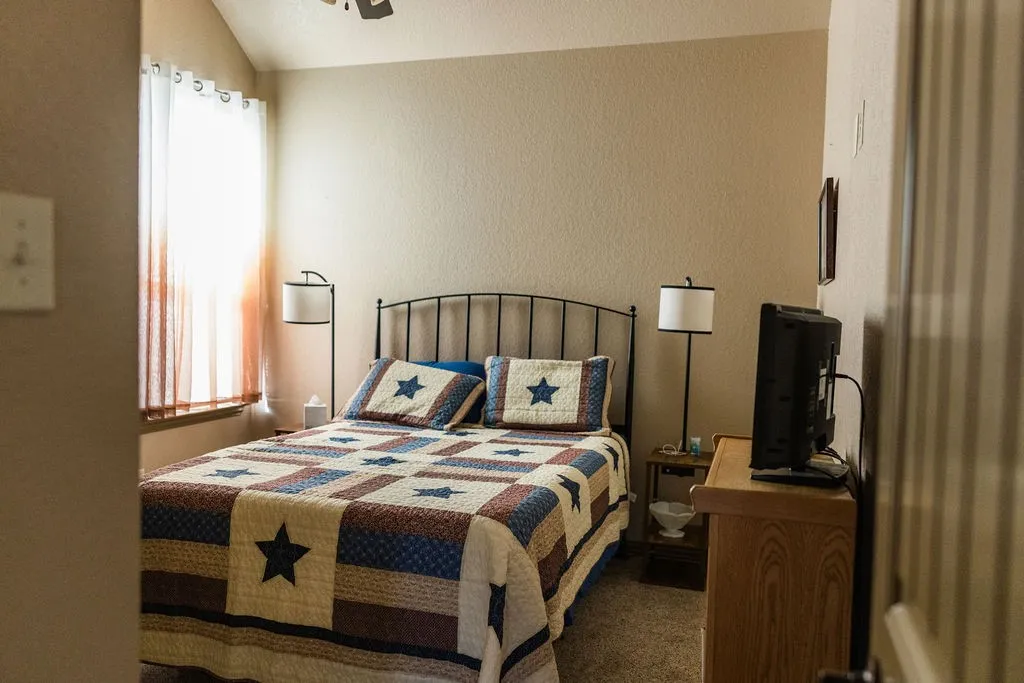 Vaulted ceiling, textured walls, carpet flooring, window with sheer curtains, recessed window
