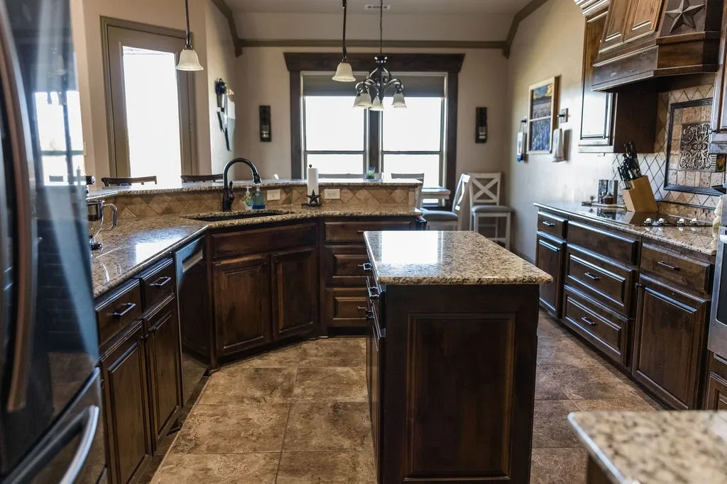 Kitchen with an island, dark wood cabinetry, granite countertops, and tile flooring