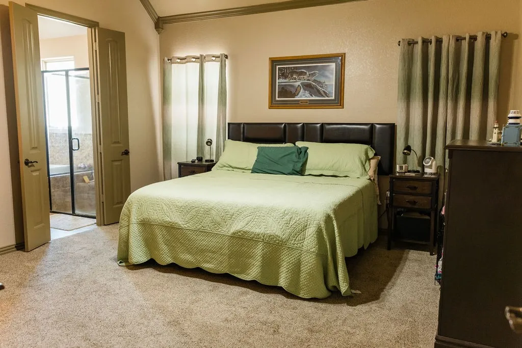 Carpeted flooring with dual entry doors, leading to a bathroom featuring a tiled shower enclosure and soaking tub