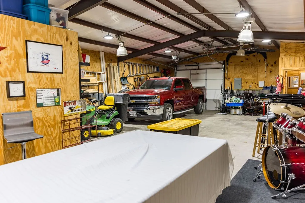 Spacious interior with an exposed beam ceiling, concrete flooring, and multiple overhead light fixtures.