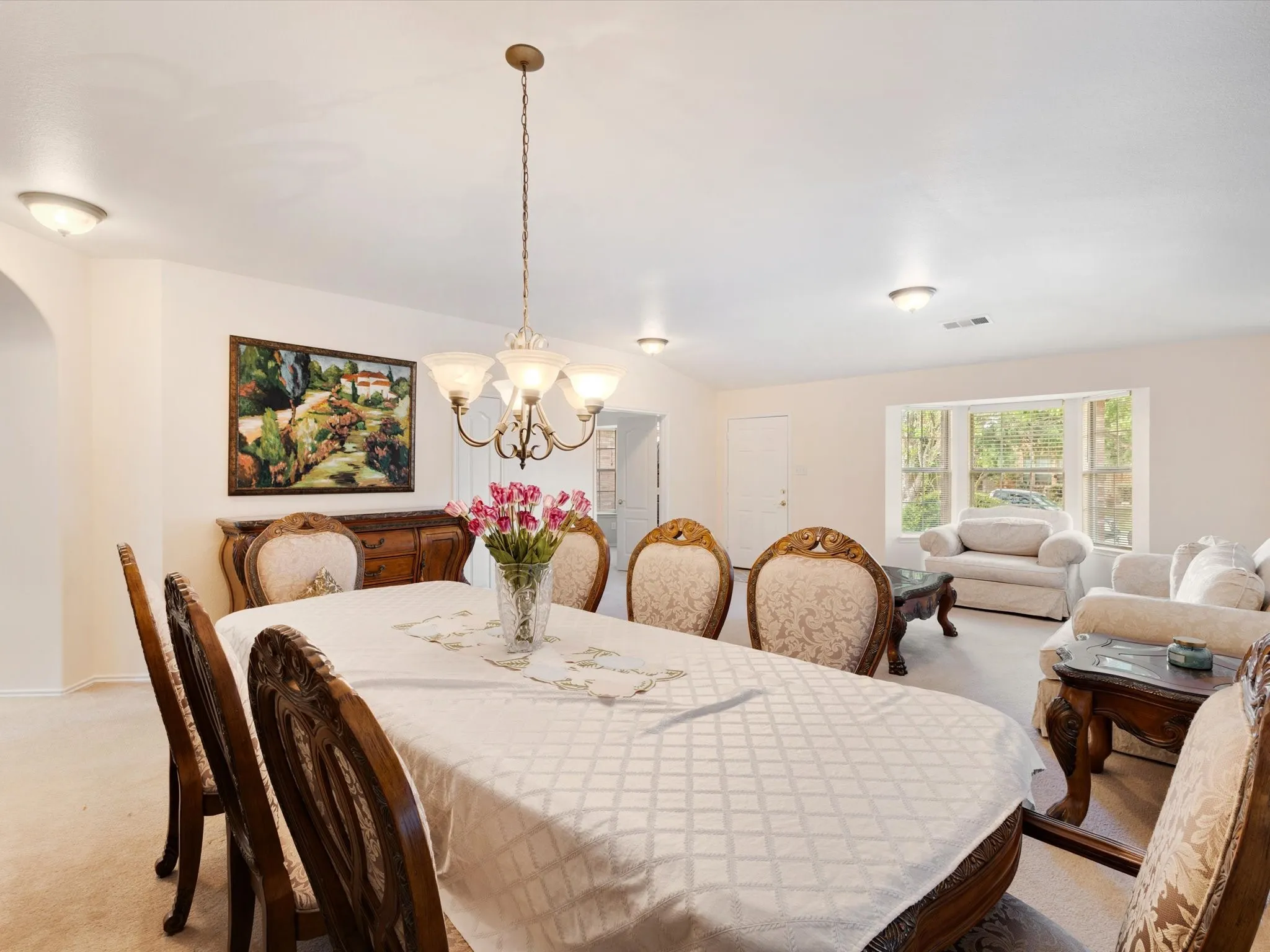 Expansive room featuring a multi-pane window, flush-mount lighting, and a decorative chandelier