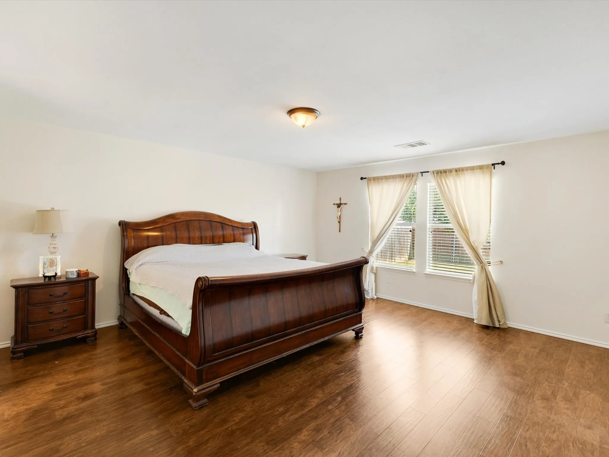 Hardwood-finish flooring, white walls, two windows with blinds, and a ceiling-mounted light fixture