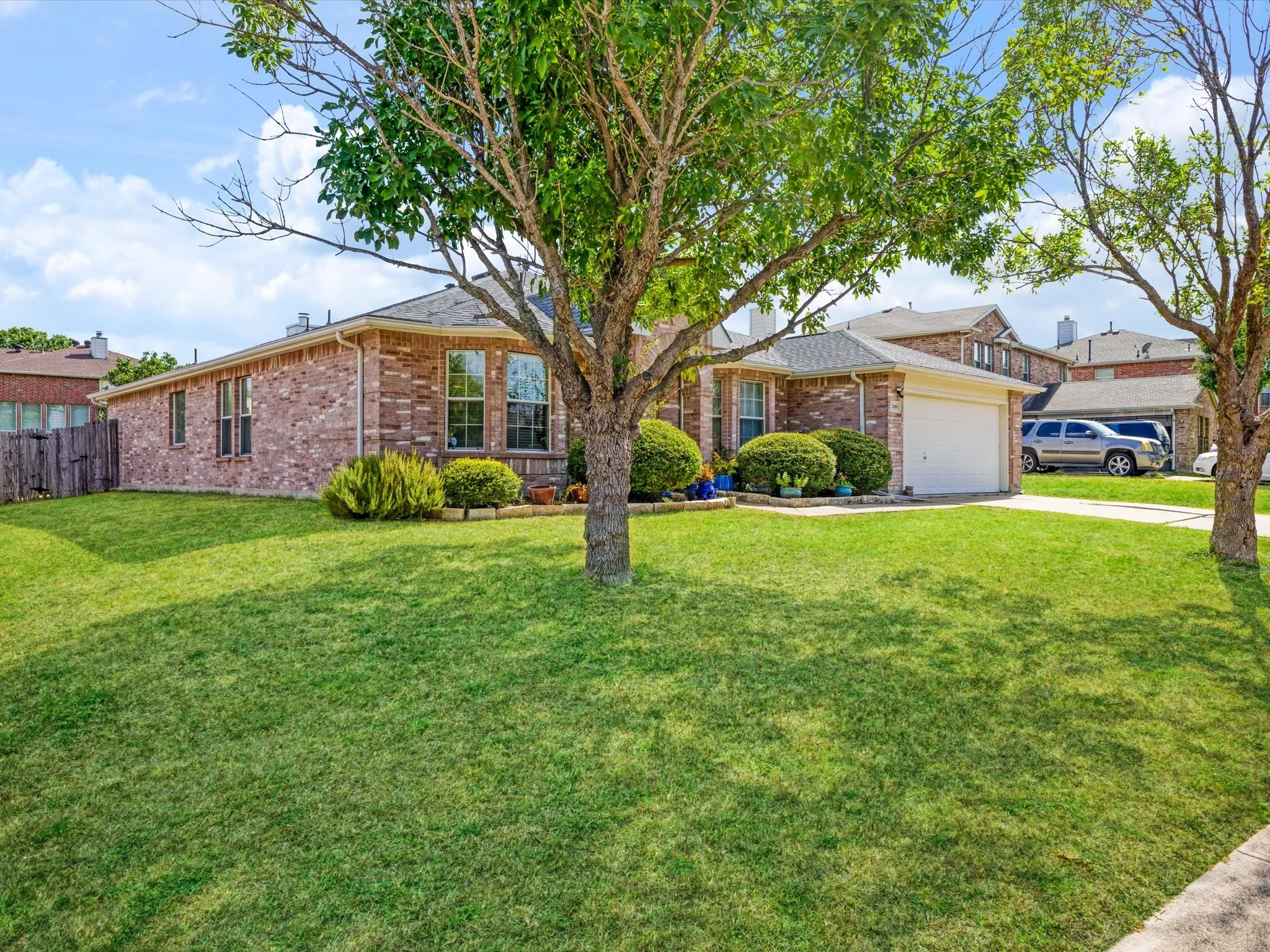 Brick exterior with an attached garage, featuring a concrete driveway and a manicured lawn