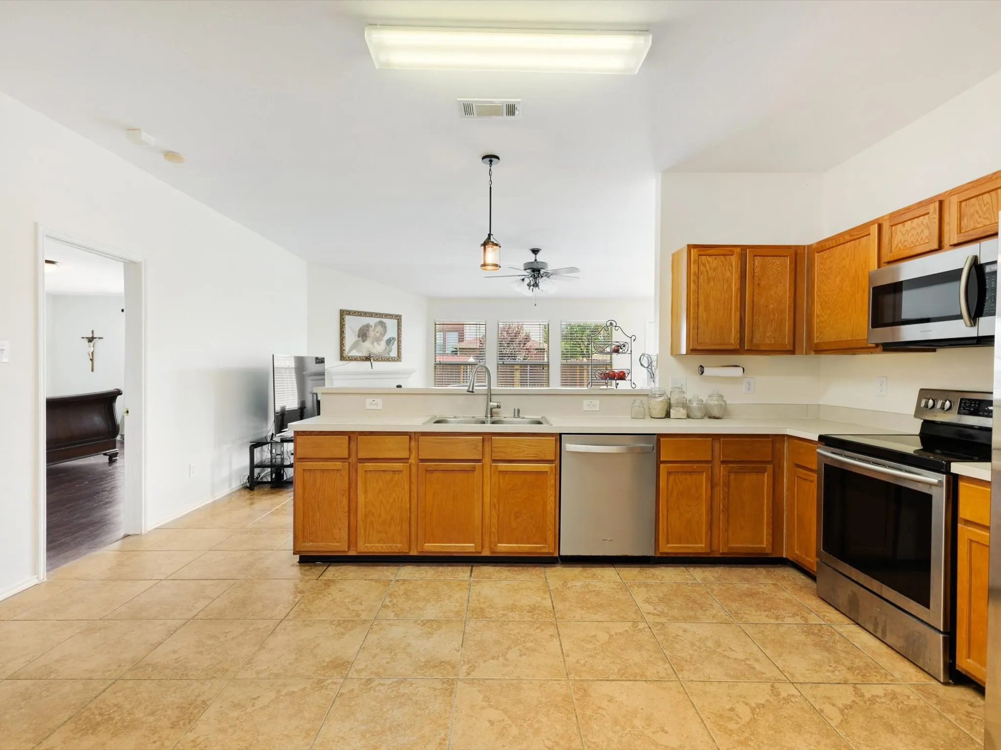 Kitchen with tile flooring, wood cabinetry, stainless steel appliances, and a pass-through counter