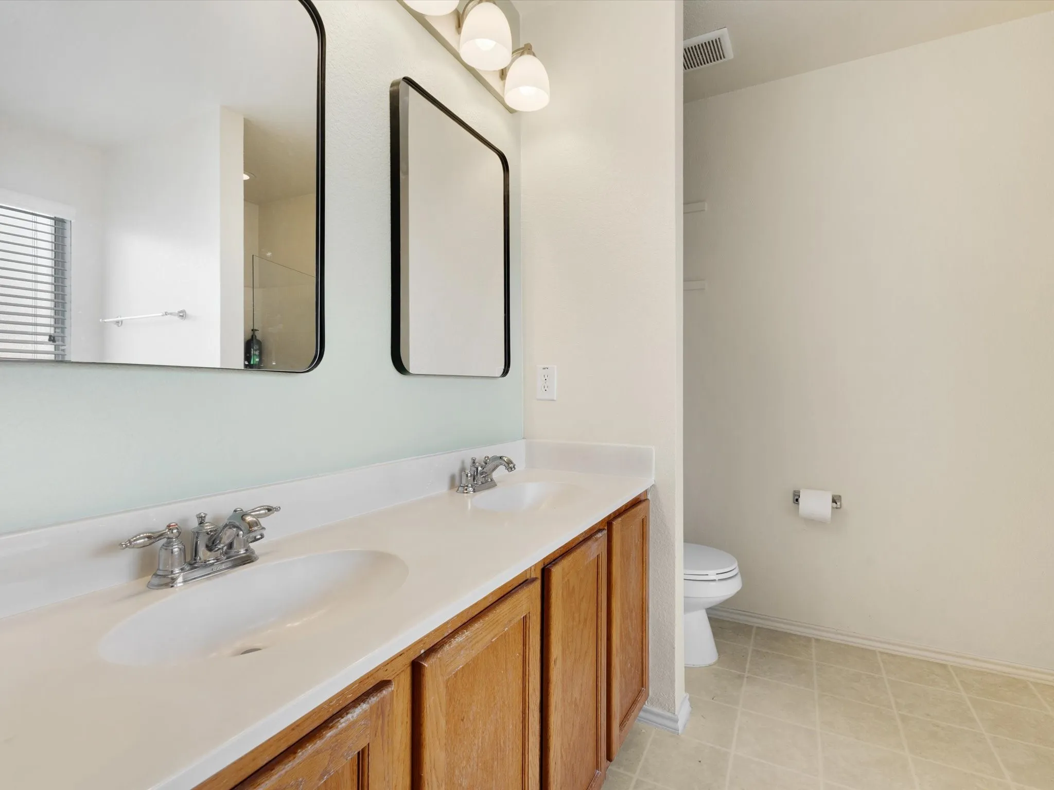 Dual vanity with white countertop and wood-finish cabinetry