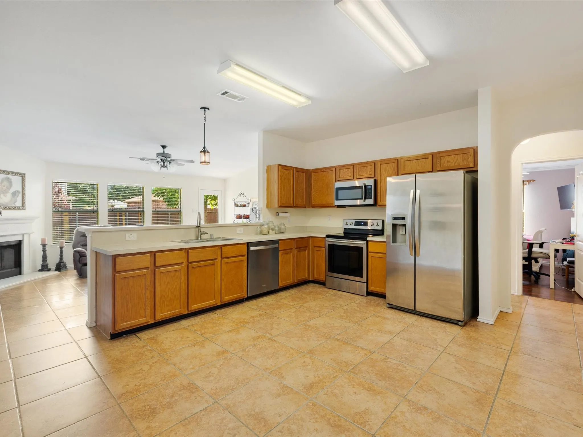 Kitchen featuring wood cabinetry, stainless steel appliances, tile flooring, and a peninsula countertop