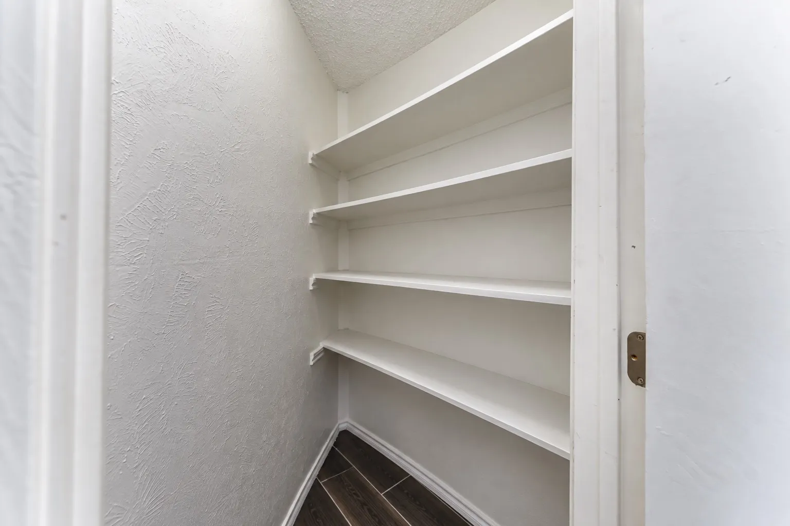 Built-in shelving for storage, wood-finish flooring, and textured wall finish