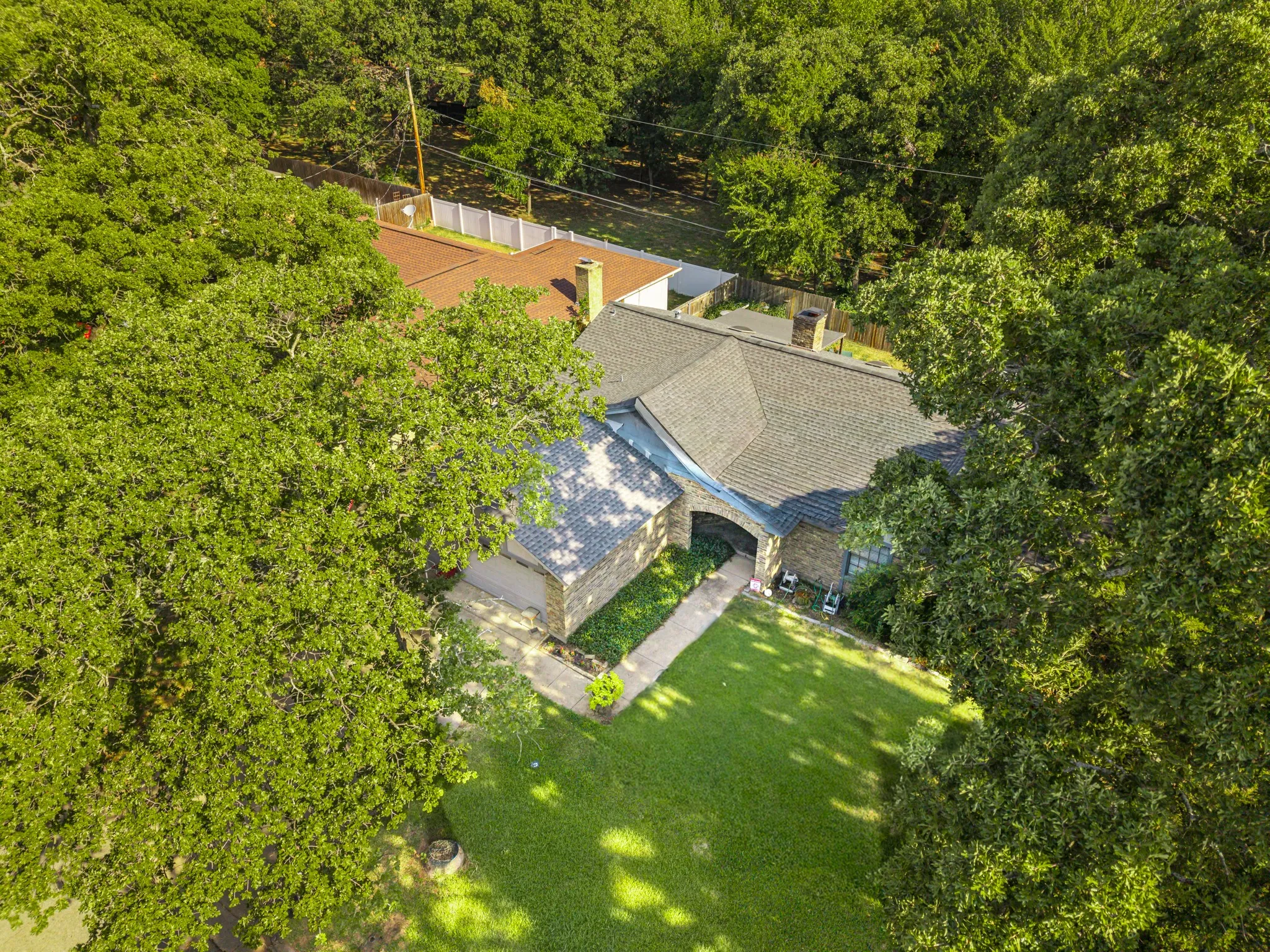 Property featuring a stone exterior, an arched entryway, and a shingle roof