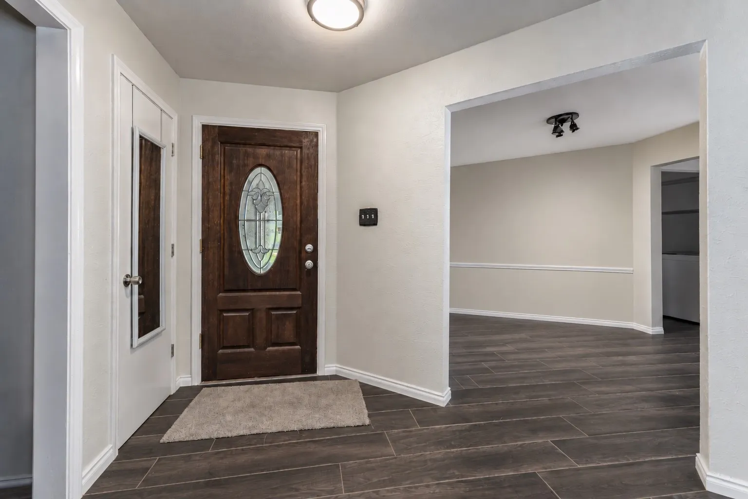 Entryway featuring a wood-panel door with an oval glass insert, recessed lighting, and wood-finish tile flooring