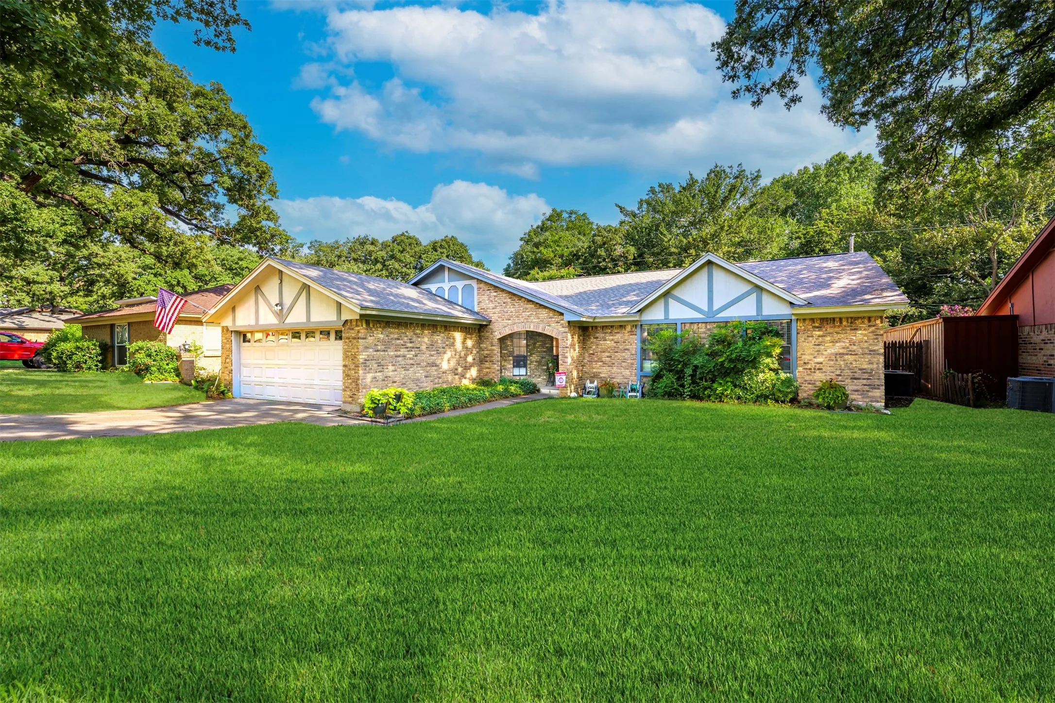 Brick facade residence featuring a two-car garage, established landscaping, and a well-maintained lawn