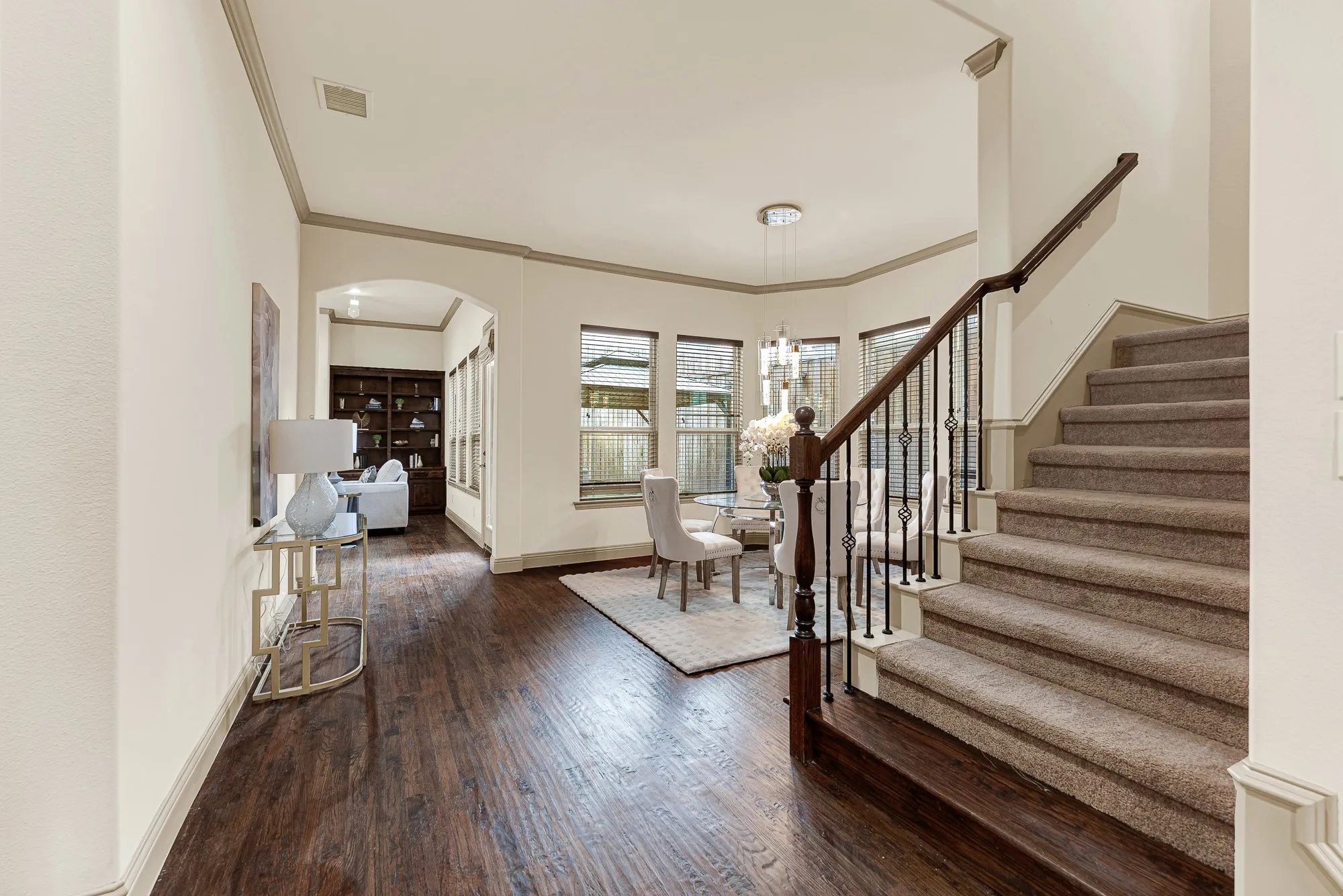 The turned-spindle staircase rail gently guides sightlines beneath an arched entryway toward the formal dining space. Envision pouring celebratory toasts here while guiding guests seamlessly toward a festive holiday dinner.