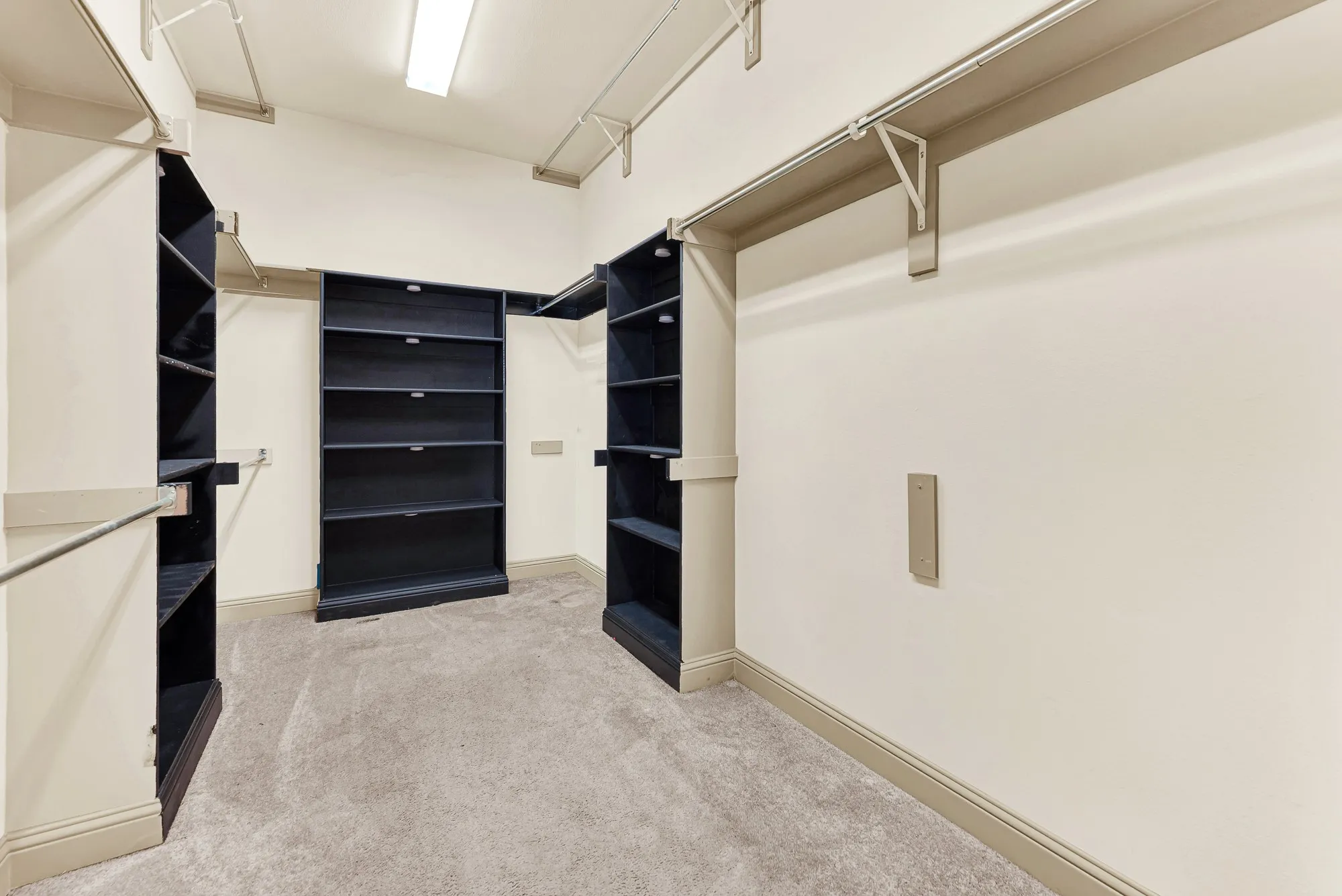 Floor-to-ceiling shelving towers and wrap-around tiered hanging rods maximize vertical storage under clean overhead lighting. Envision easily coordinating seasonal wardrobes and selecting attire for work or formal gatherings with everything in plain view.