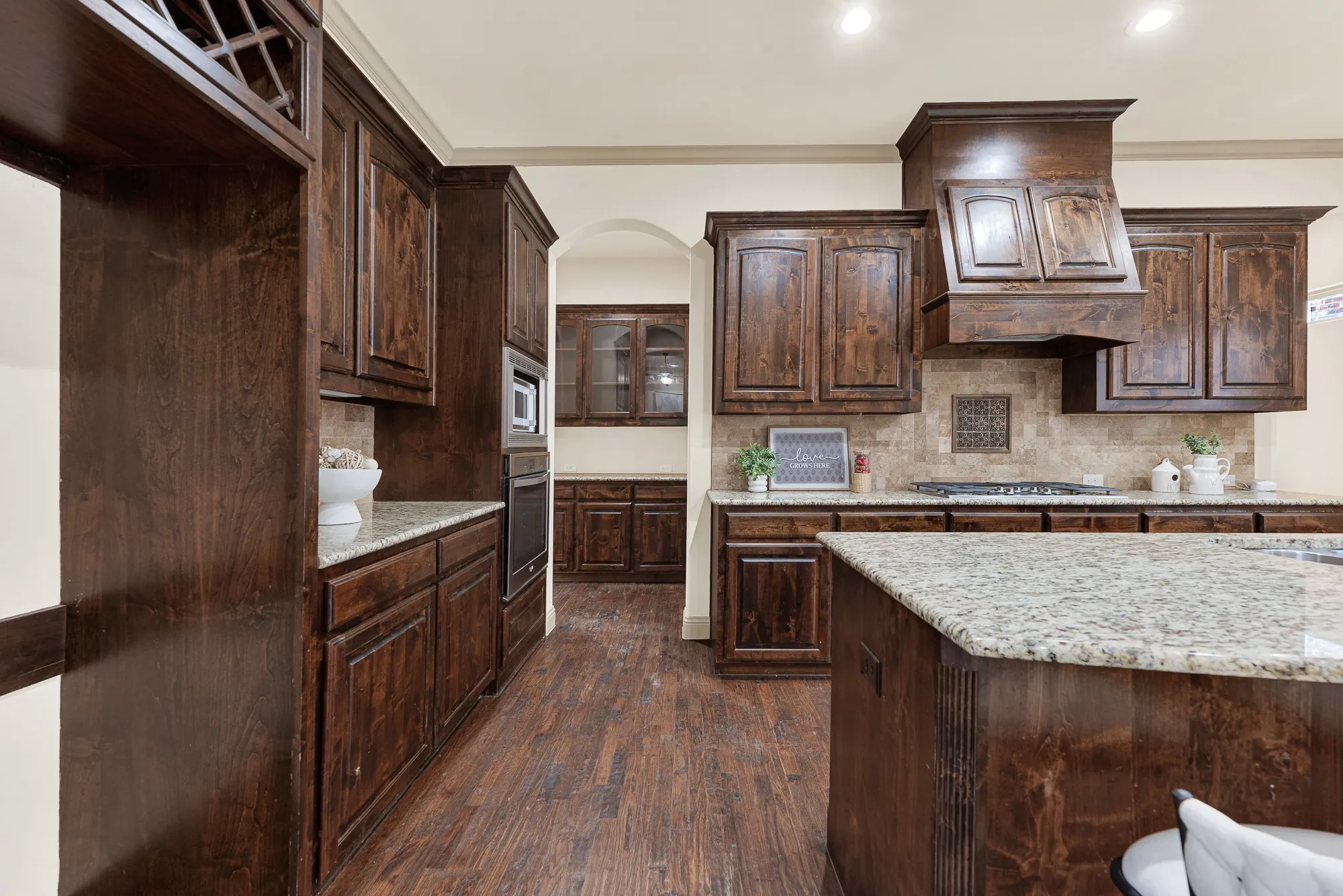 Built-in wine cubbies frame the upper alcove, leading the eye toward the arched butler’s pass-through. It’s built for quiet evening tastings, pouring a vintage cabernet straight from the rack before guests arrive.