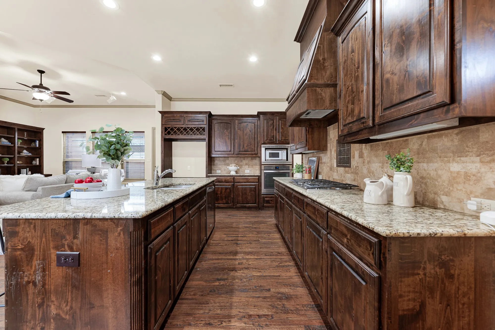 Deep granite worktops flank the recessed gas cooktop, providing generous culinary prep zones along the main aisle. Feel the joy of simmering fragrant, slow-cooked sauces while easily conversing across the open prep space.
