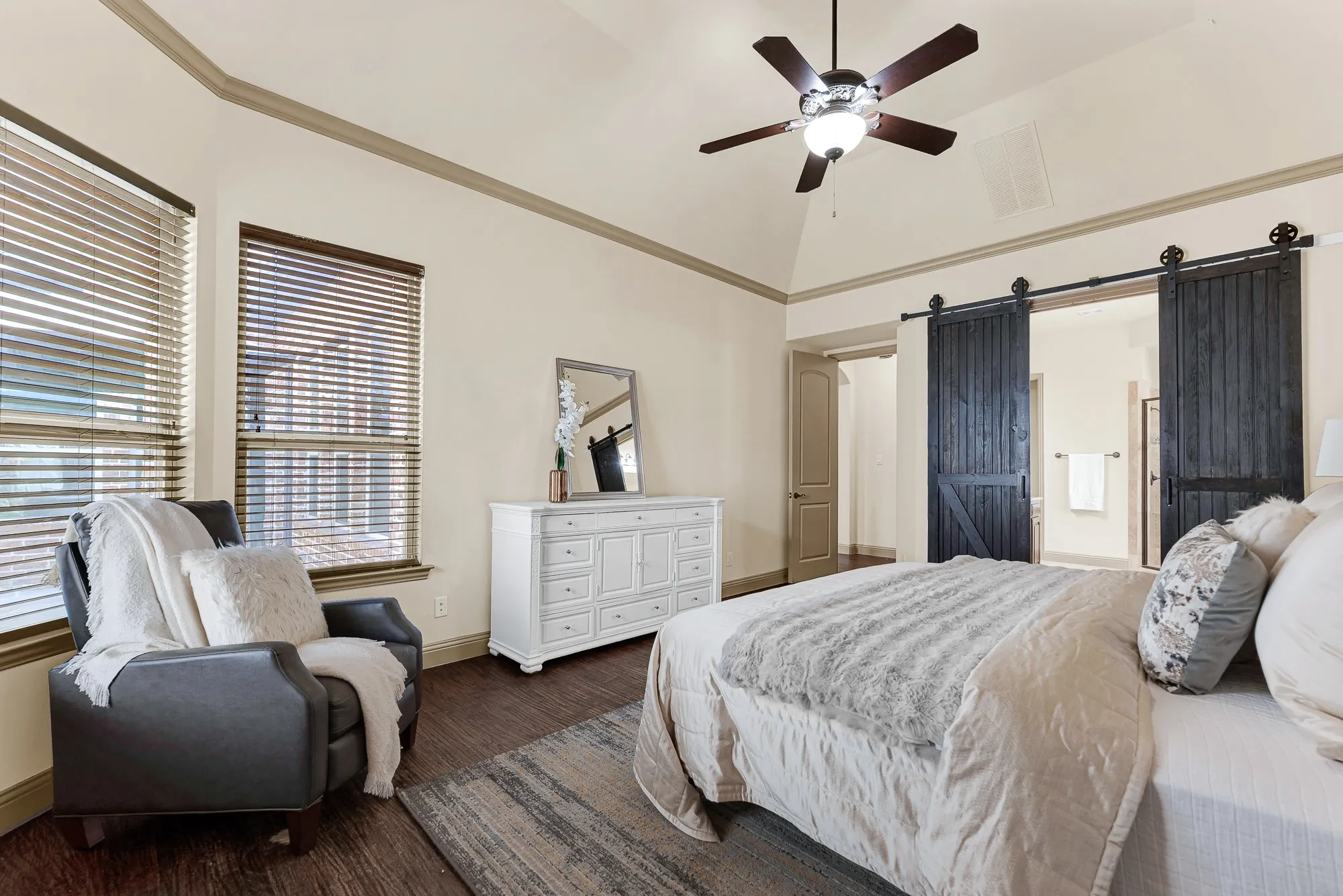 Rustic black double barn doors on matte iron tracking form a bold entryway to the en-suite bath. It sets the tone for tranquil nighttime wind-downs, sliding the doors open for a warm, restorative soak.