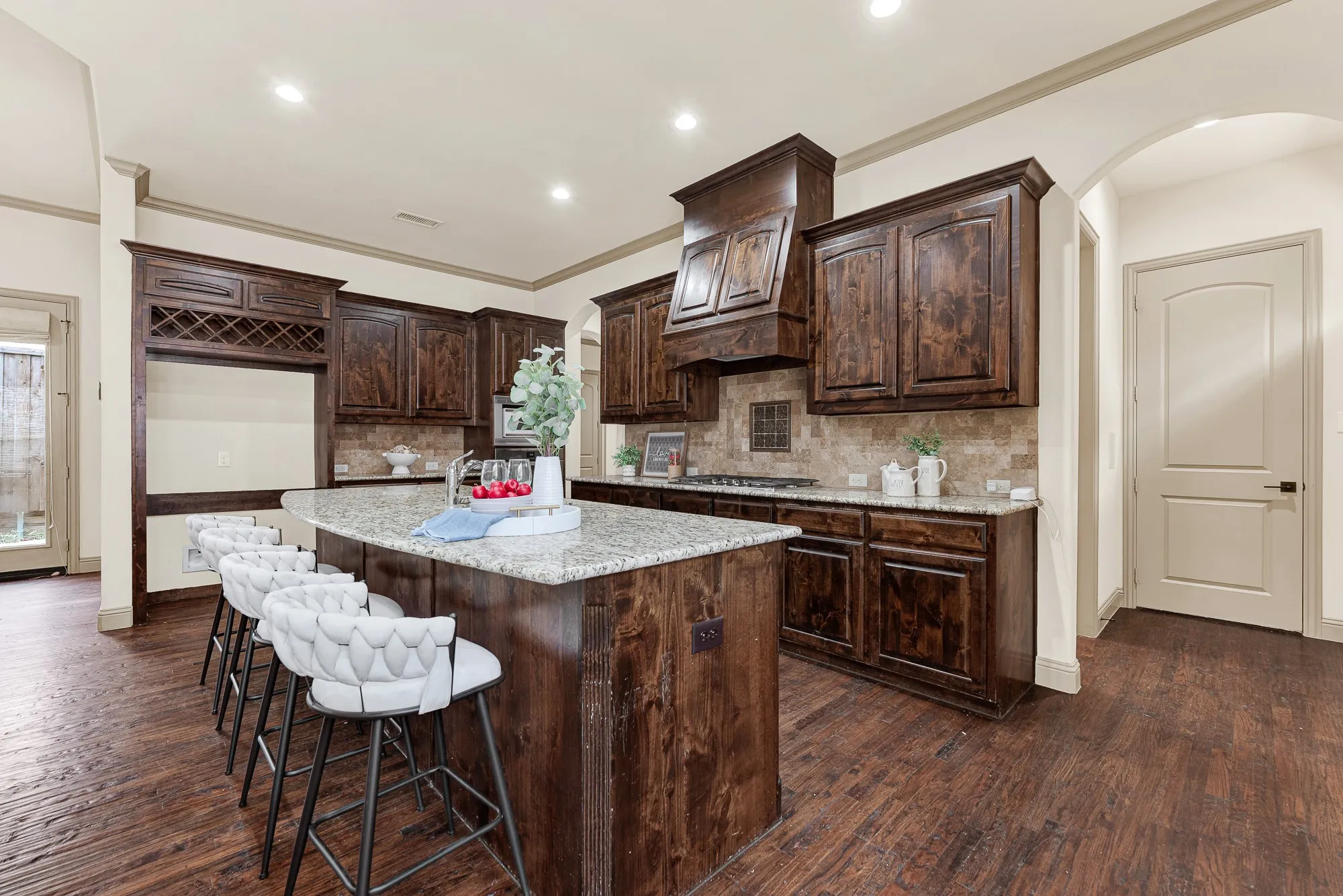 Fluted wooden corner millwork on the island and sweeping arched entryways lend refined architectural texture to the workspace. Envision setting out an abundant charcuterie spread here as weekend entertaining naturally kicks into gear.
