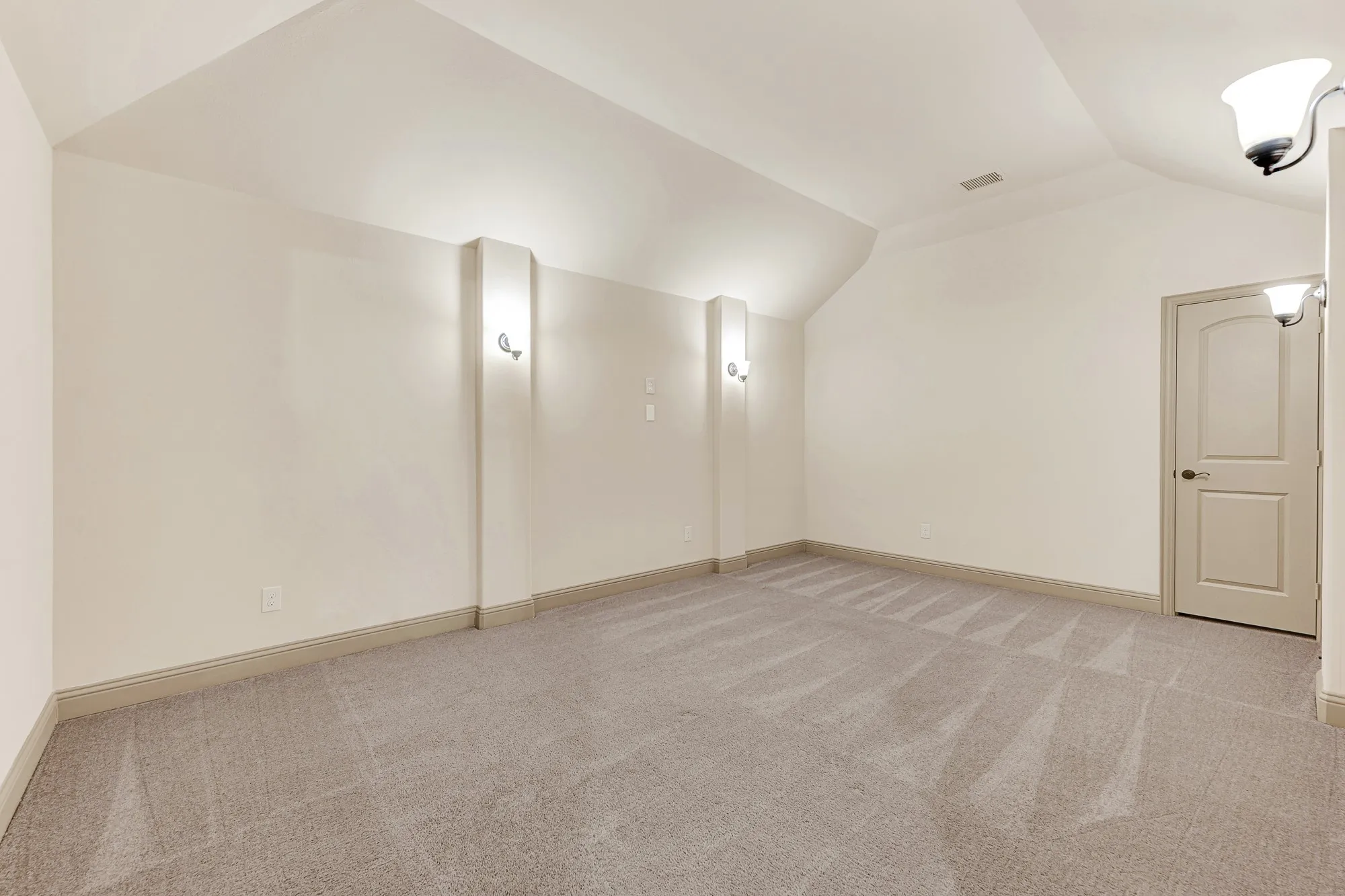 Vertical architectural pilasters topped with soft sconce lighting frame a deep acoustic niche beneath gentle ceiling angles. Picture hosting memorable movie marathons or cheering on your favorite sports team from comfy theater recliners.