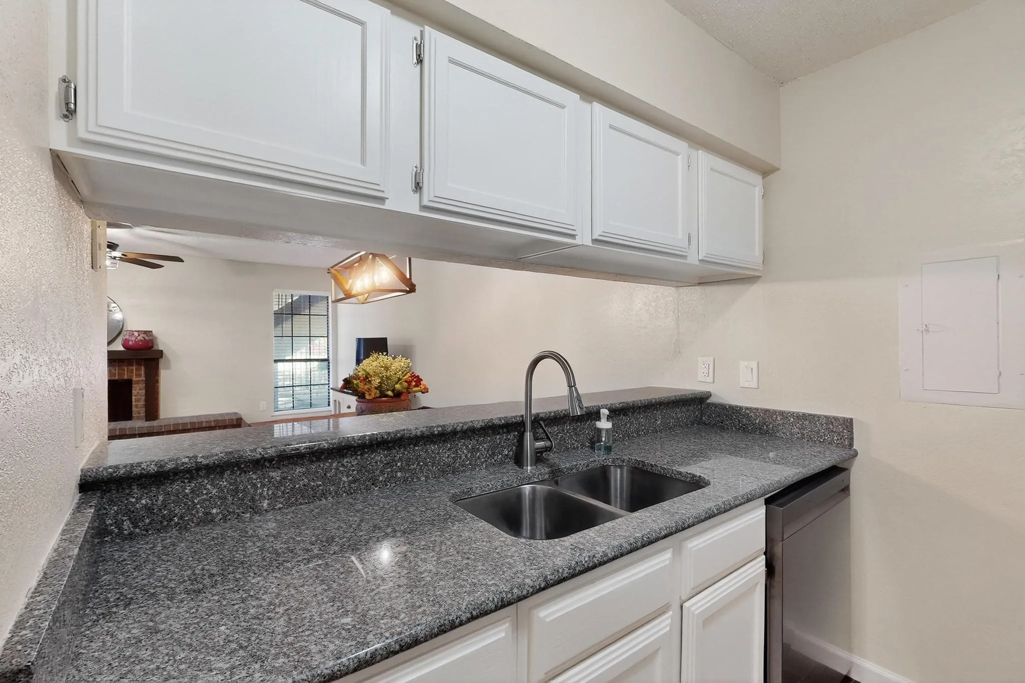 Kitchen featuring white cabinetry, gray speckled countertops, a double basin stainless steel sink with a high arc faucet, and a stainless steel dishwasher