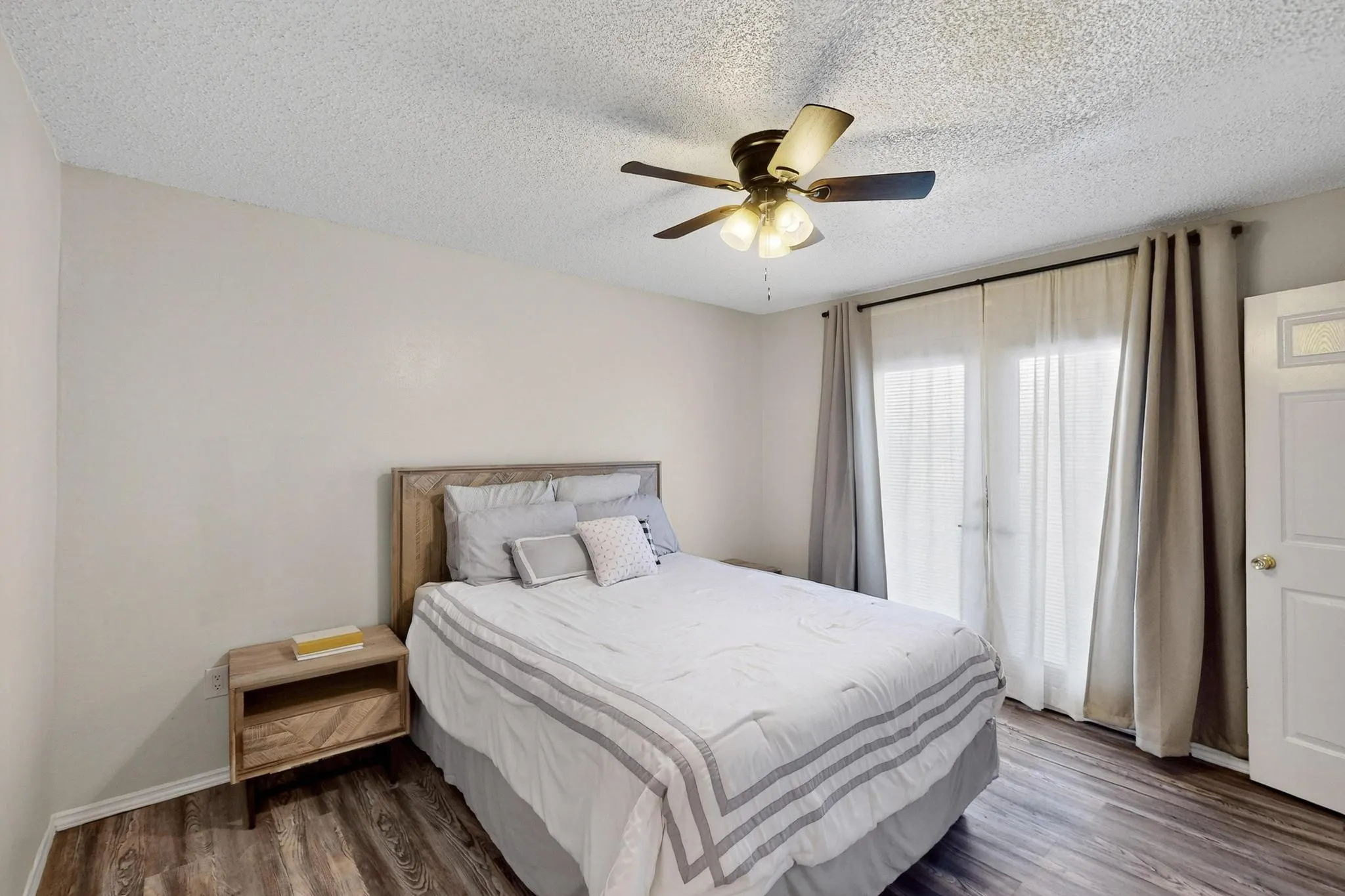 Wood-finish flooring, ceiling fan with integrated lighting, and a white door with frosted glass insert
