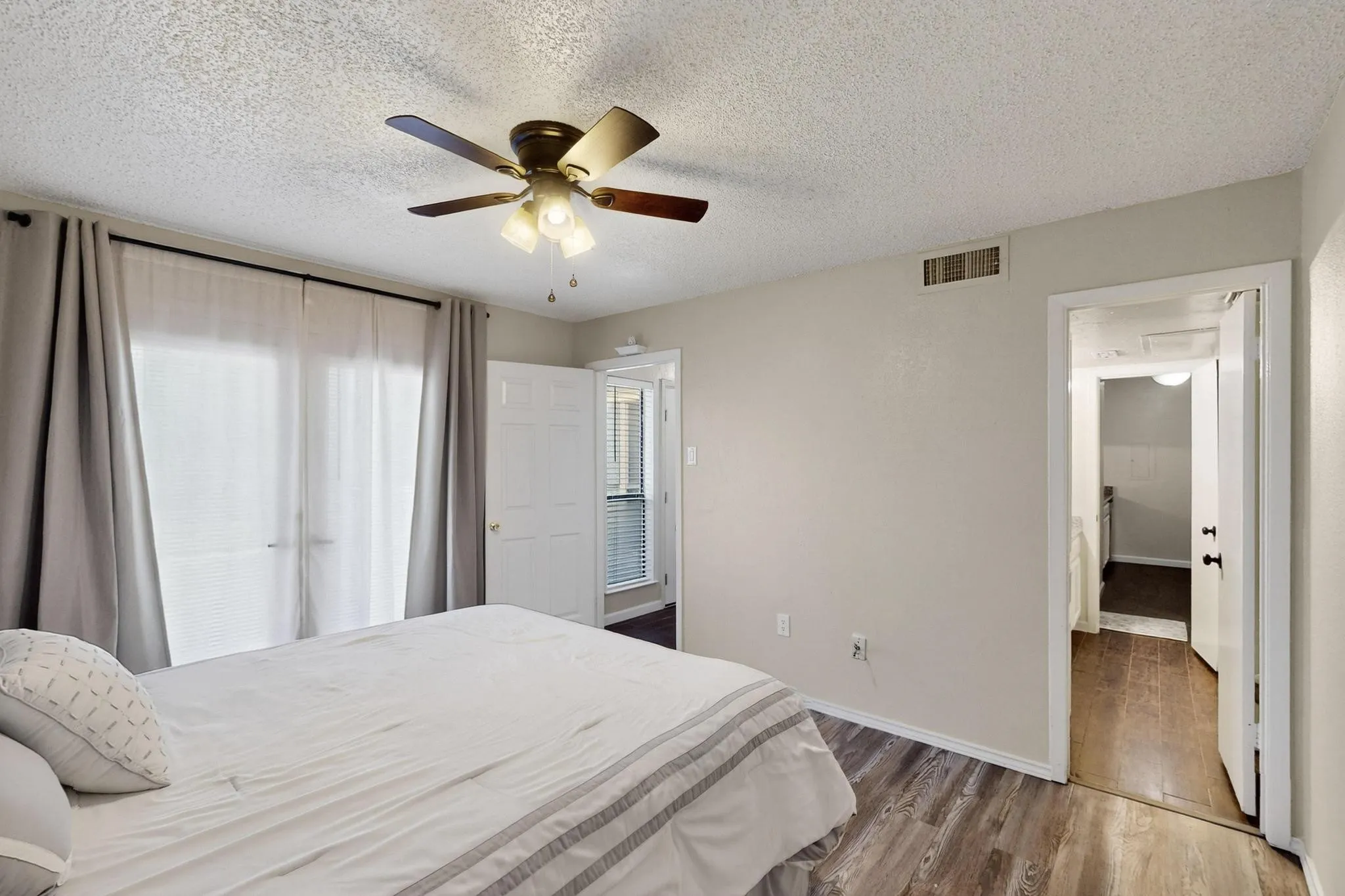 Ceiling fan with integrated lighting, wood-finish flooring, and white interior doors