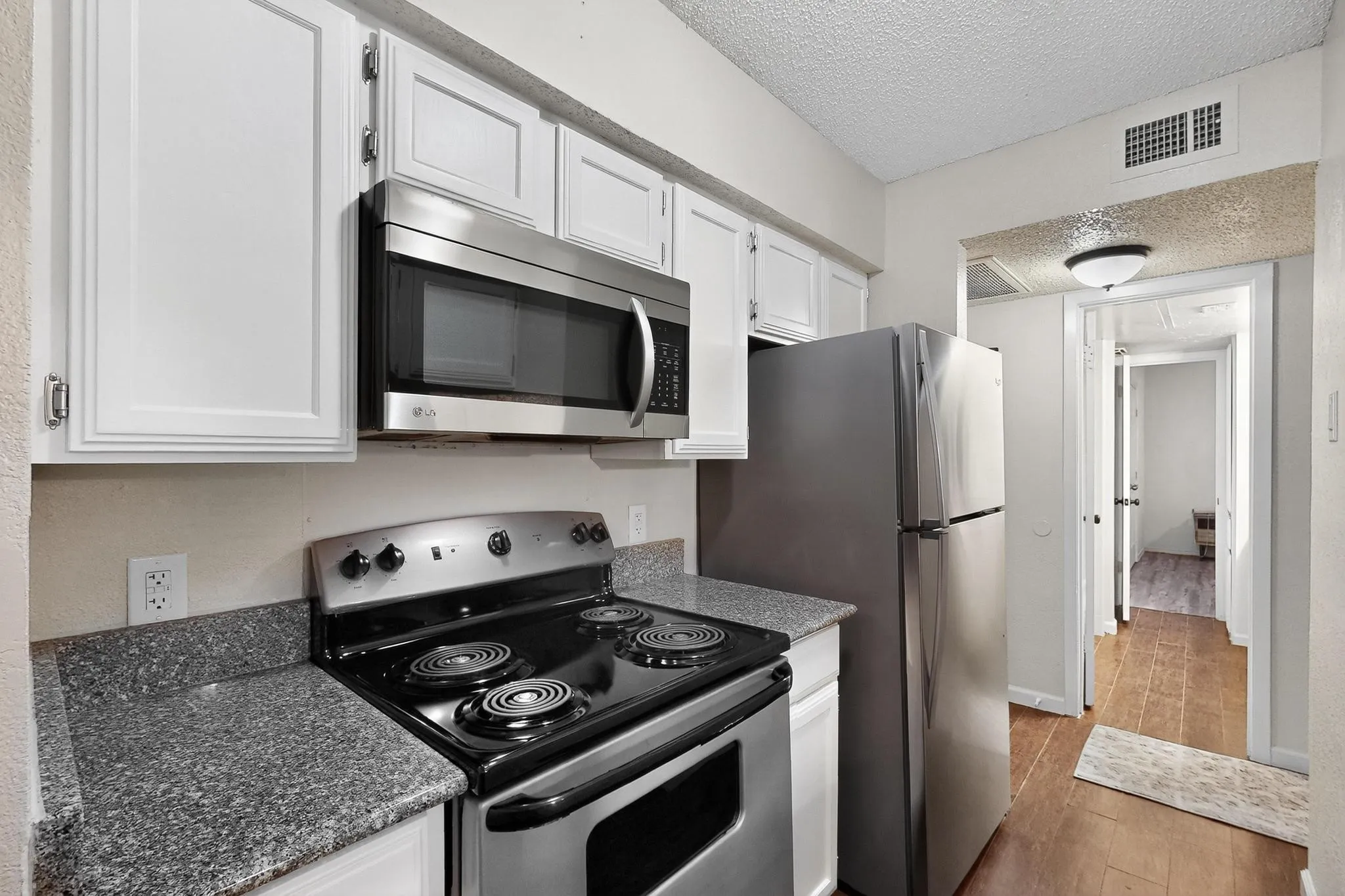 Kitchen featuring white cabinetry, a stainless steel microwave, a black electric range, a stainless steel refrigerator INCLUDED