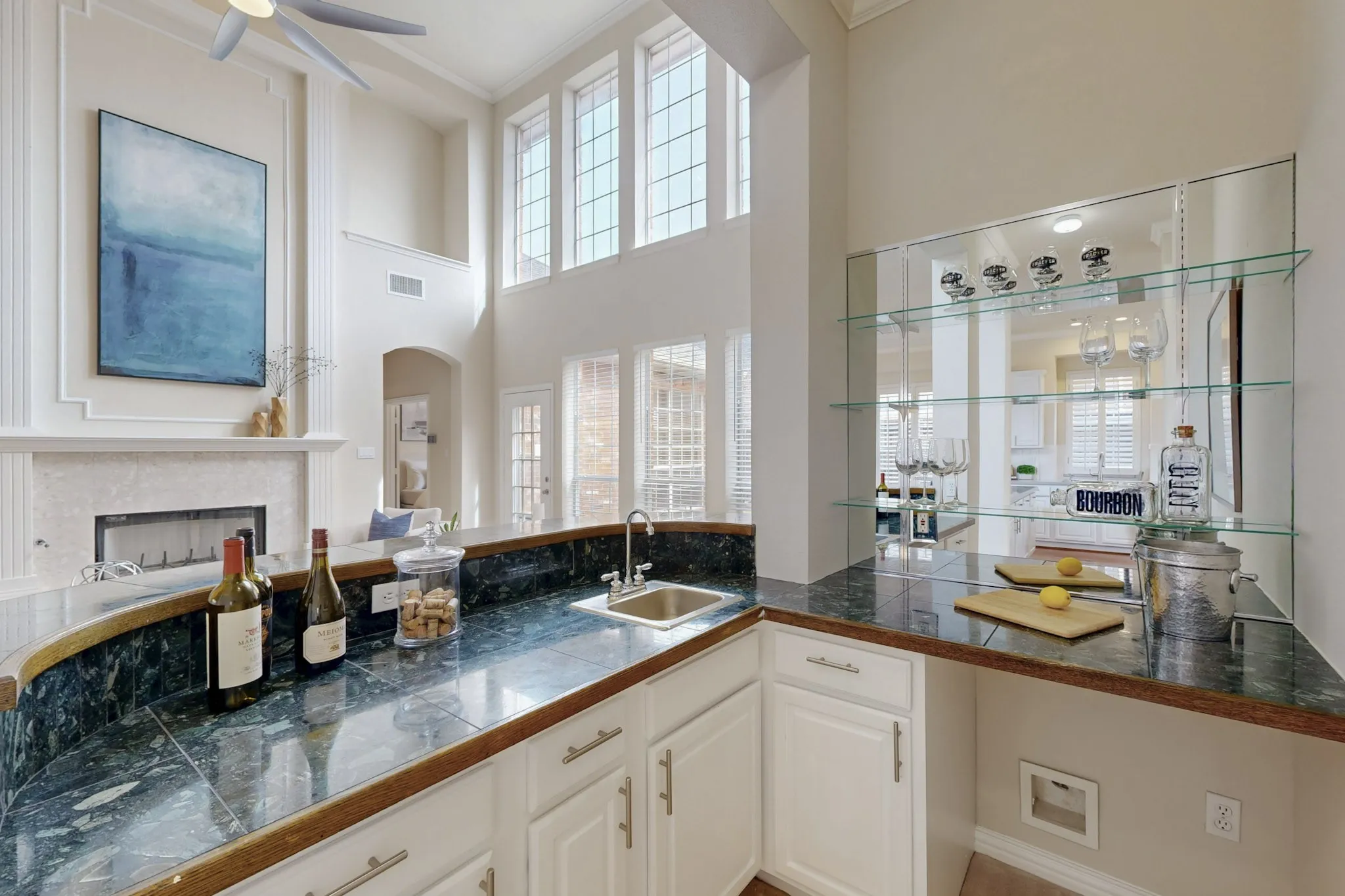 Entertain in style with a built-in wet bar overlooking the living room, featuring granite counters, glass shelving, and a convenient prep sink
