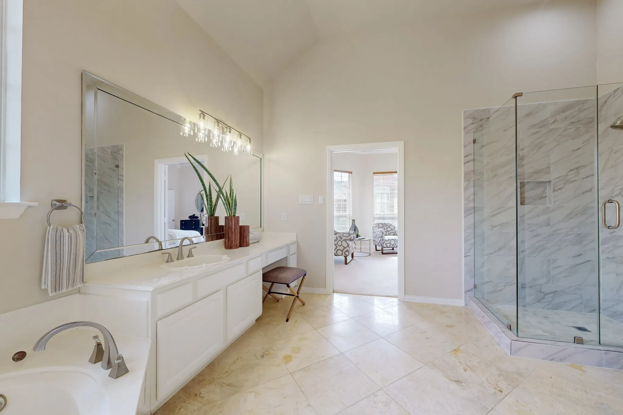 Luxurious primary bath featuring dual vanities, soaring ceilings, marble-inspired finishes, and an oversized frameless glass shower