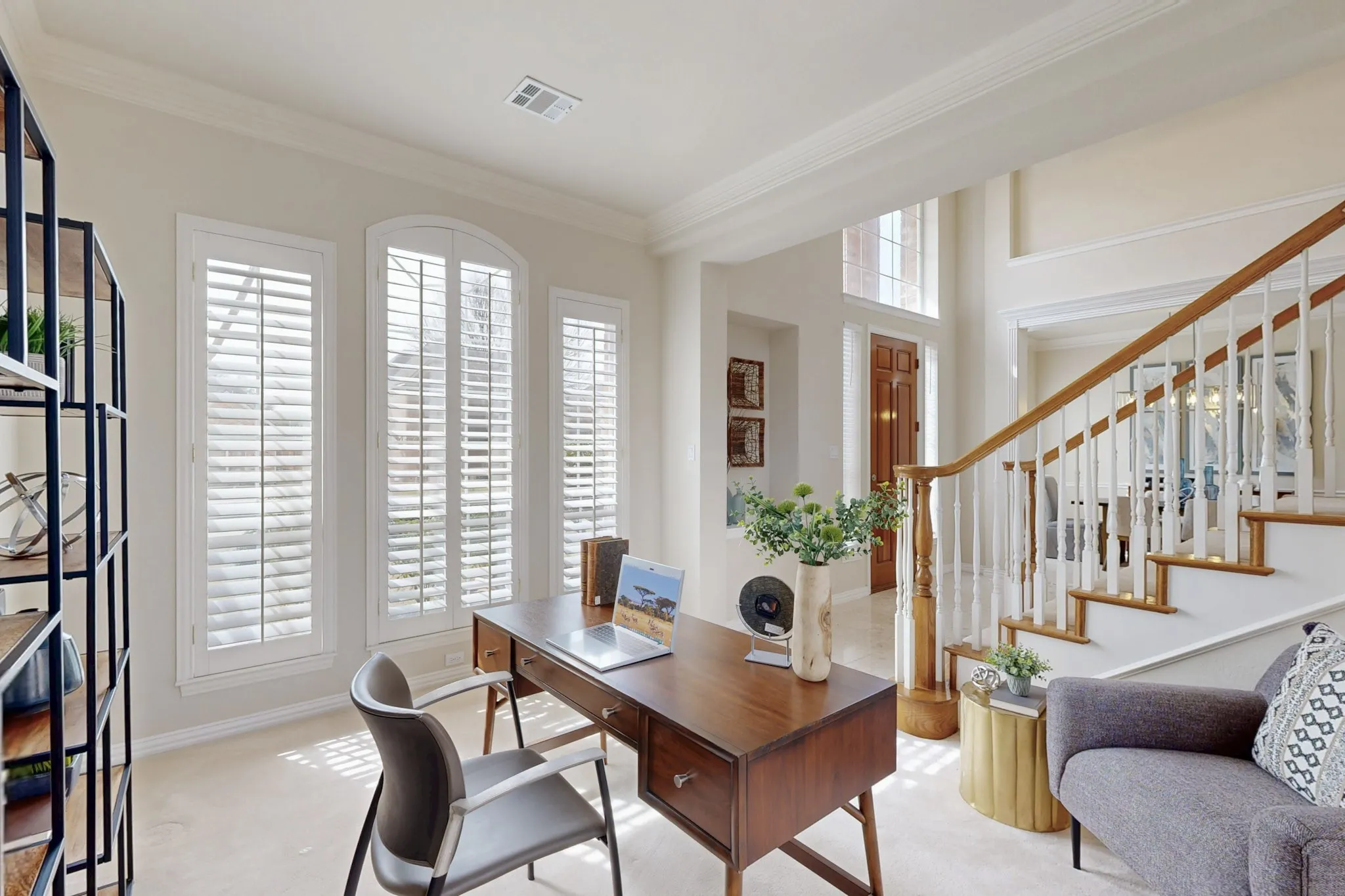 Bright home office featuring plantation shutters, abundant natural light, and elegant built-in style details